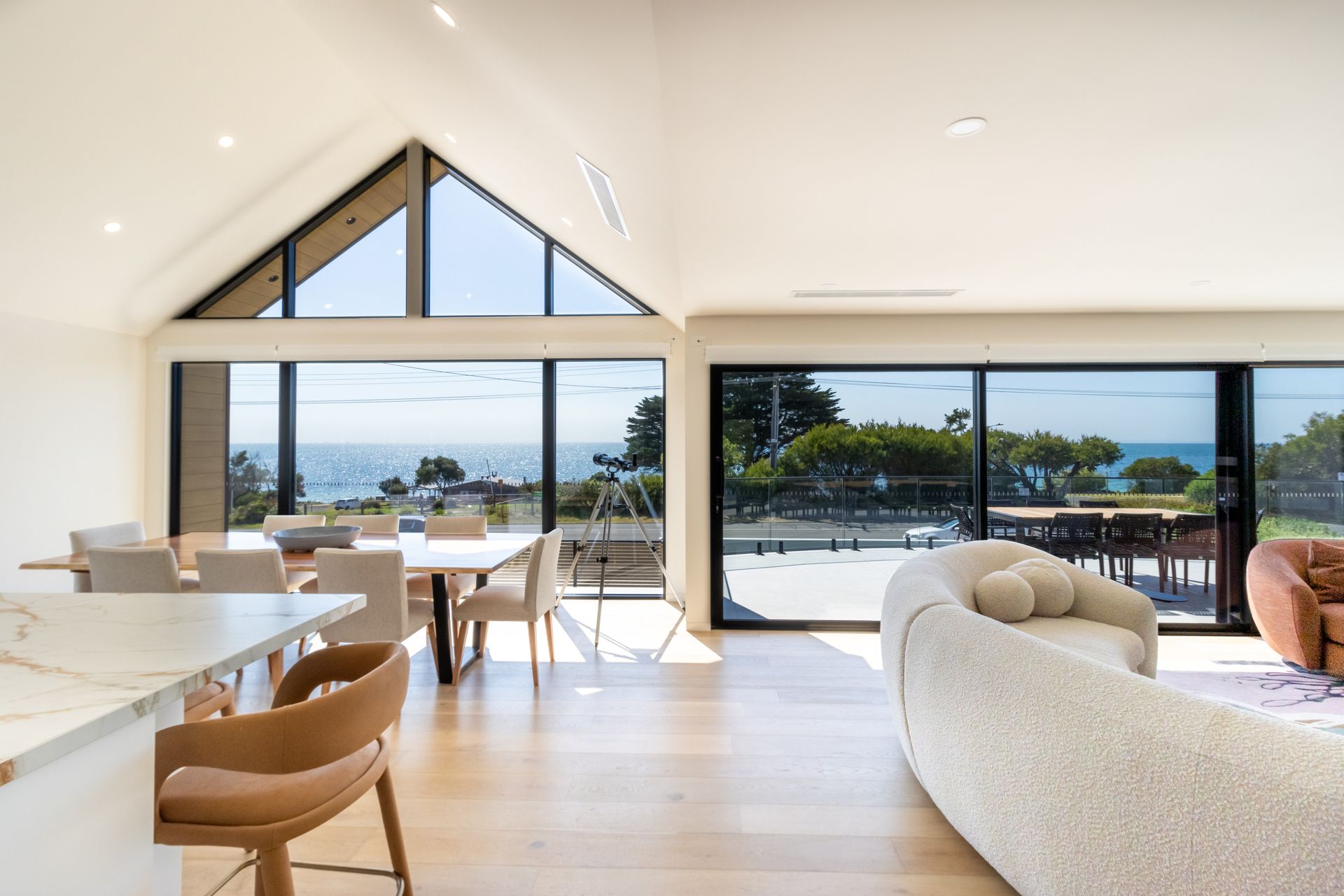 A living room with a couch , table and chairs and a view of the ocean.