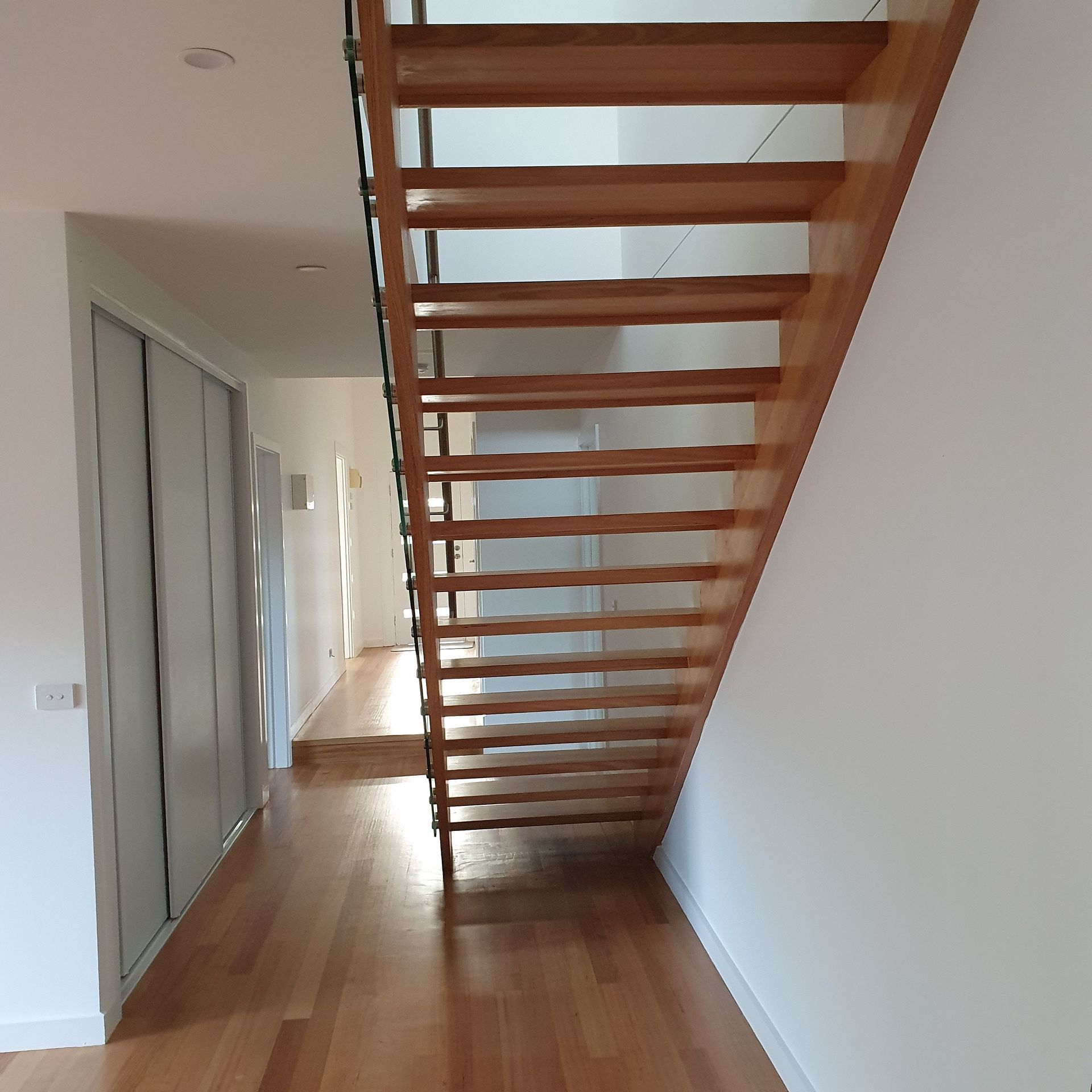A wooden staircase in a hallway with white walls  | Building Services | Coastyle