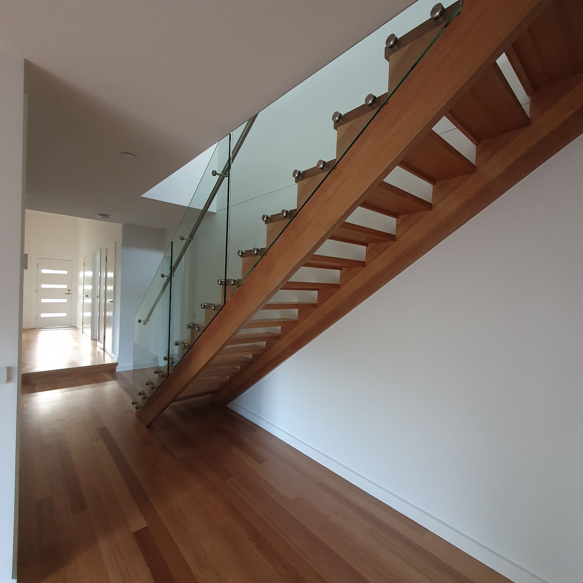 A wooden staircase with a glass railing in a hallway  | Building Services | Coastyle