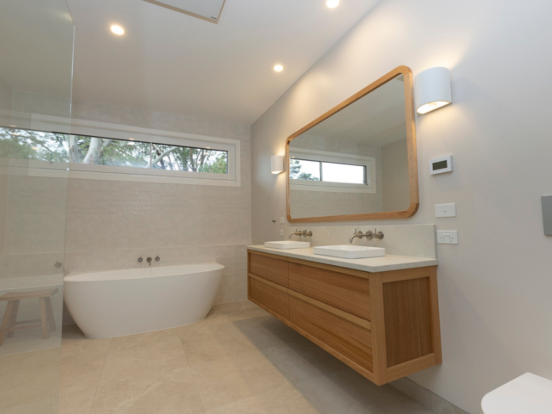 A bathroom with two sinks and a large mirror Building Services | Coastyle