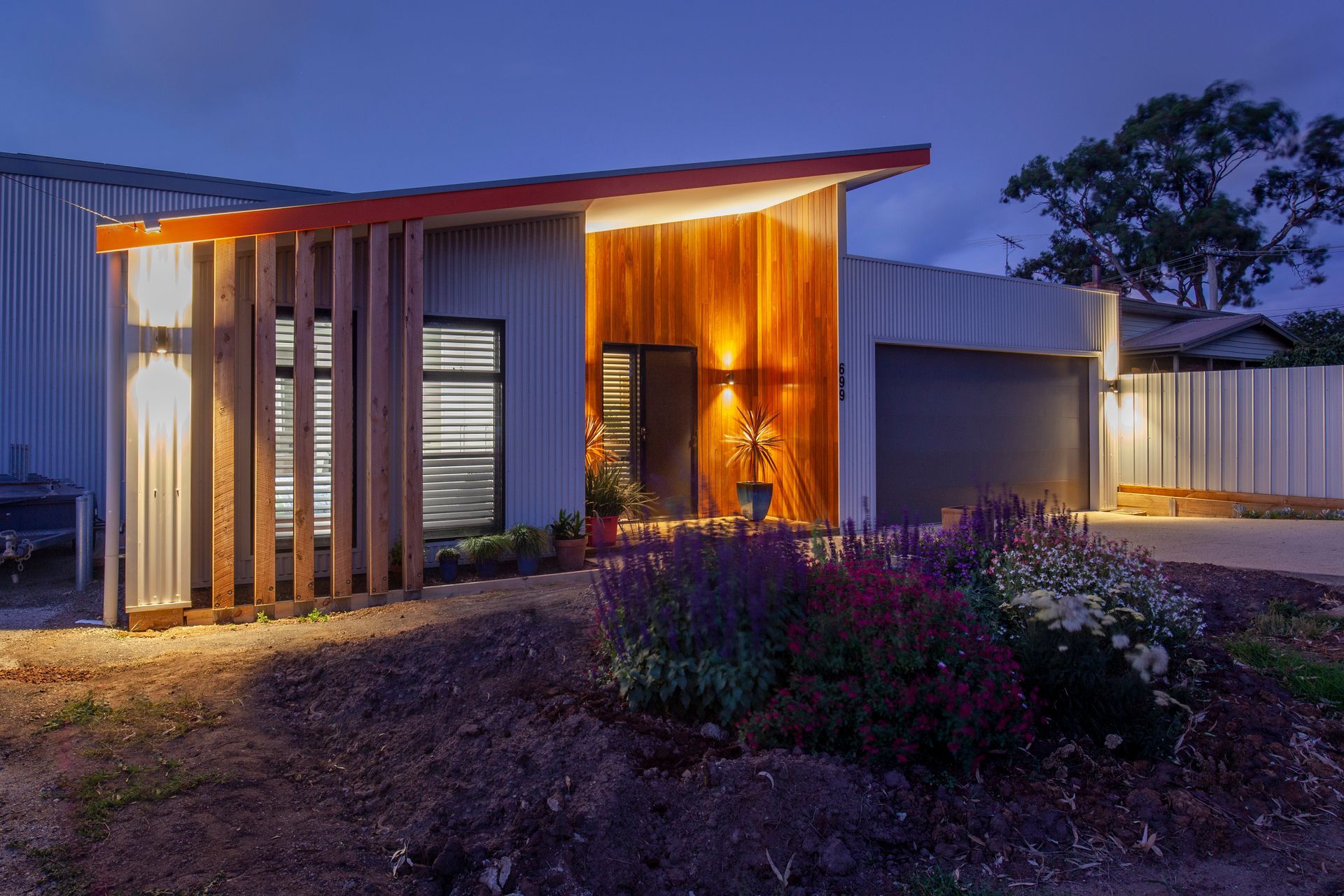 A house with a garage and a driveway is lit up at night.