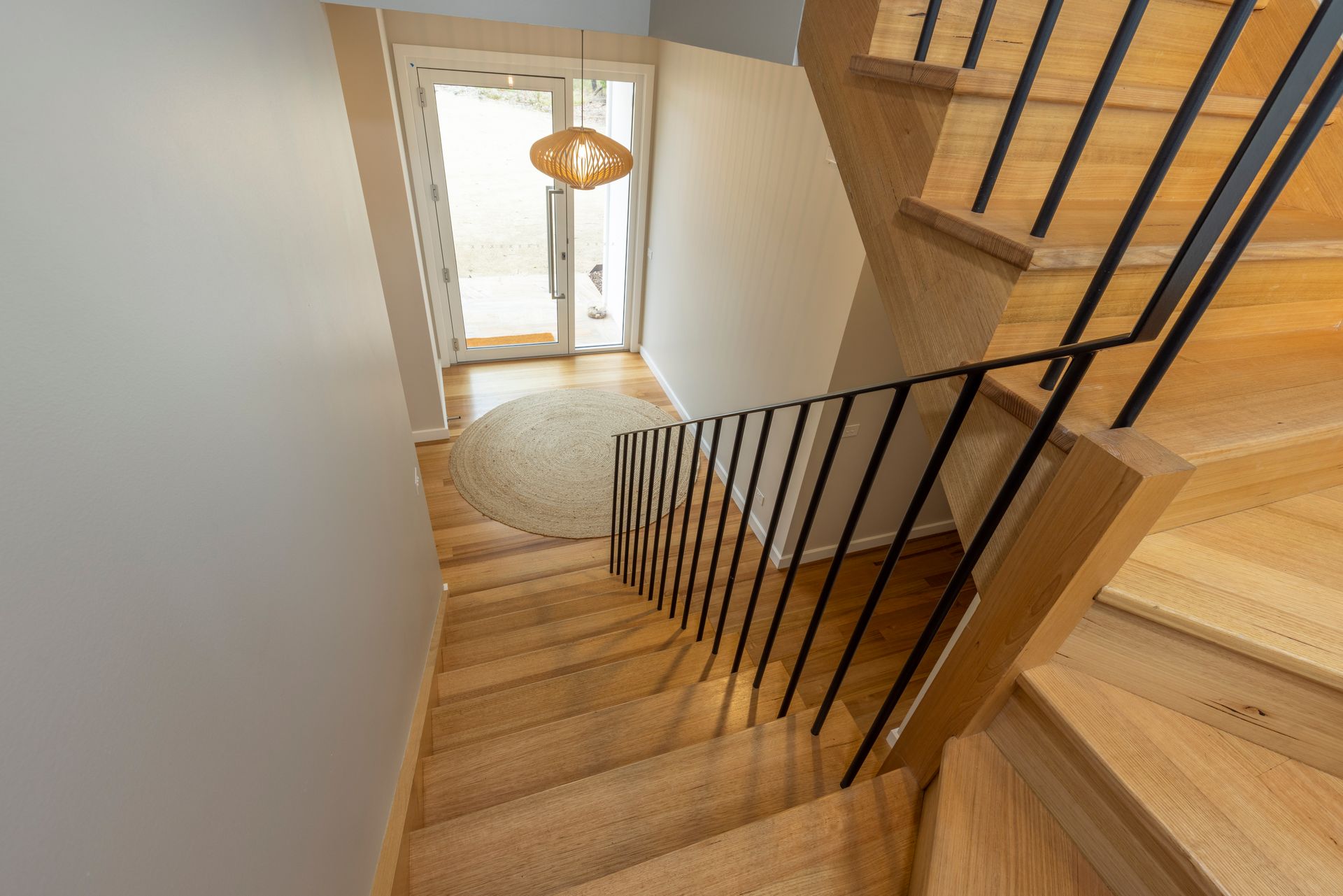 A wooden staircase with a metal railing leading up to the second floor of a house | Building Services | Coastyle
