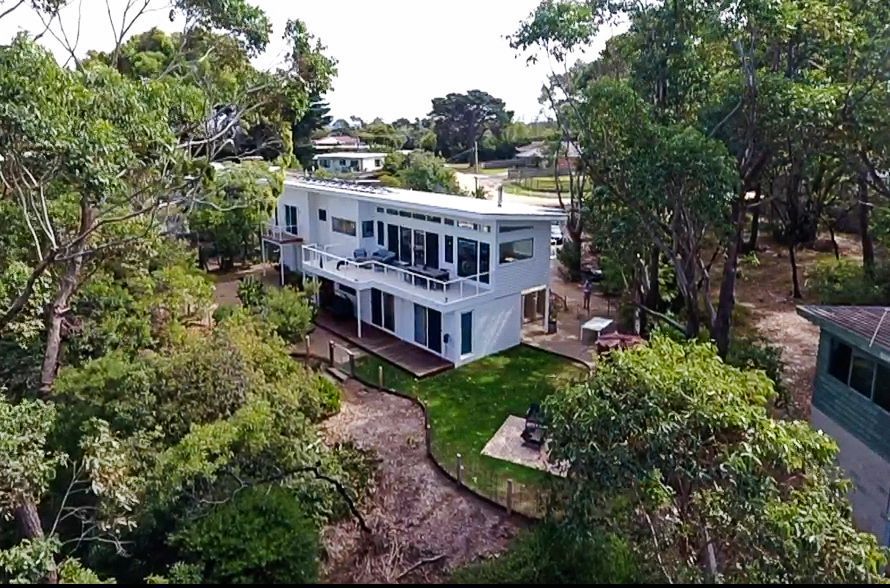 An aerial view of a large white house surrounded by trees