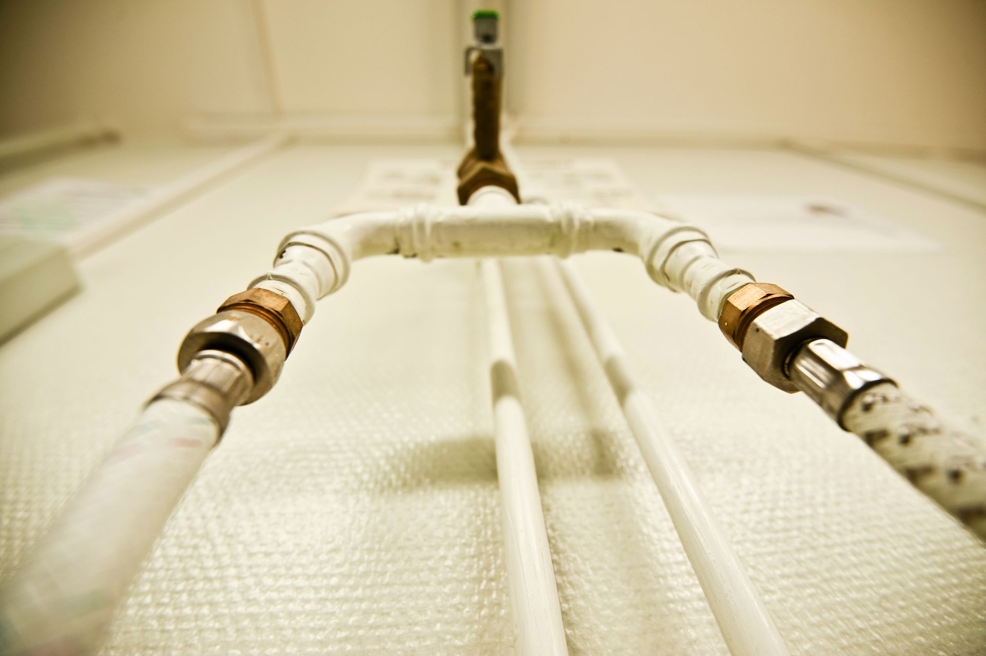 White pipes and fittings on a wall, with metal connectors.