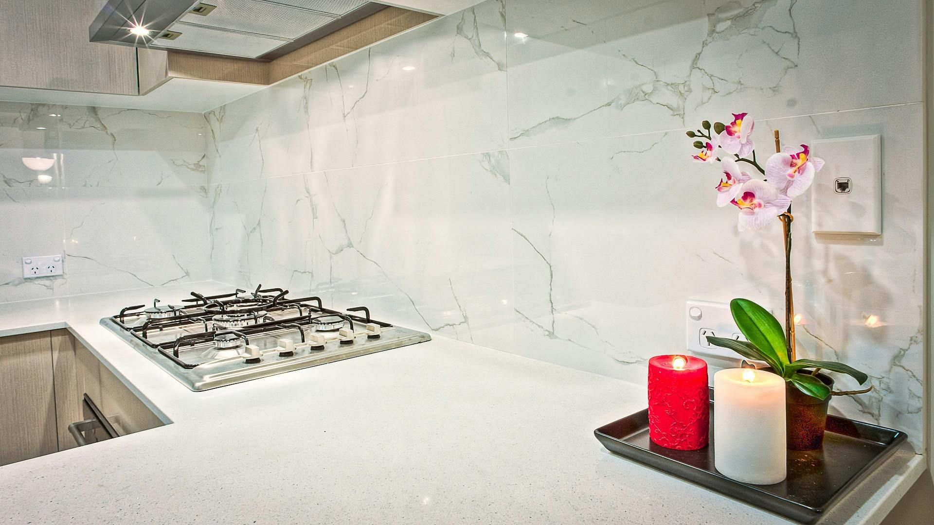 A kitchen counter with two candles and a flower on it