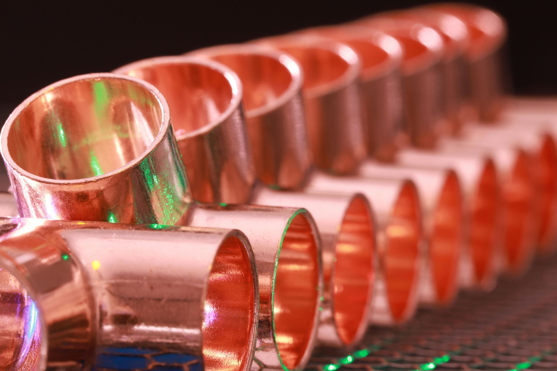 Copper pipes are lined up in a row on a table.