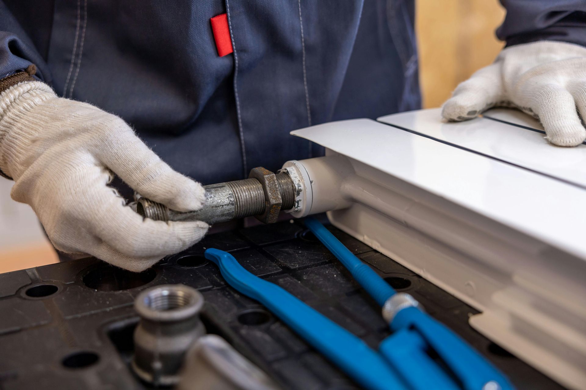 A man is fixing a radiator with a pair of pliers.