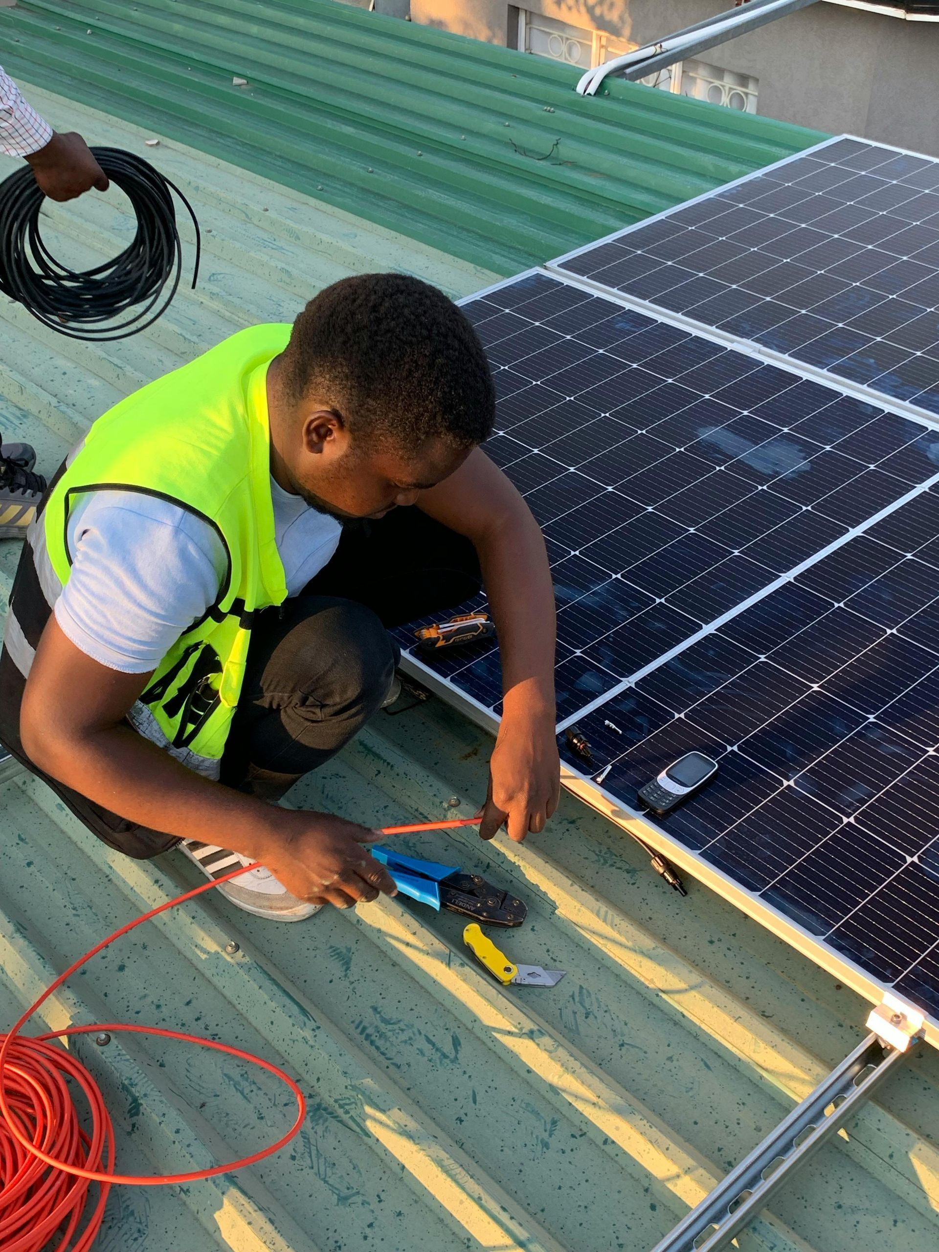 A man is working on a solar panel on the roof of a building.