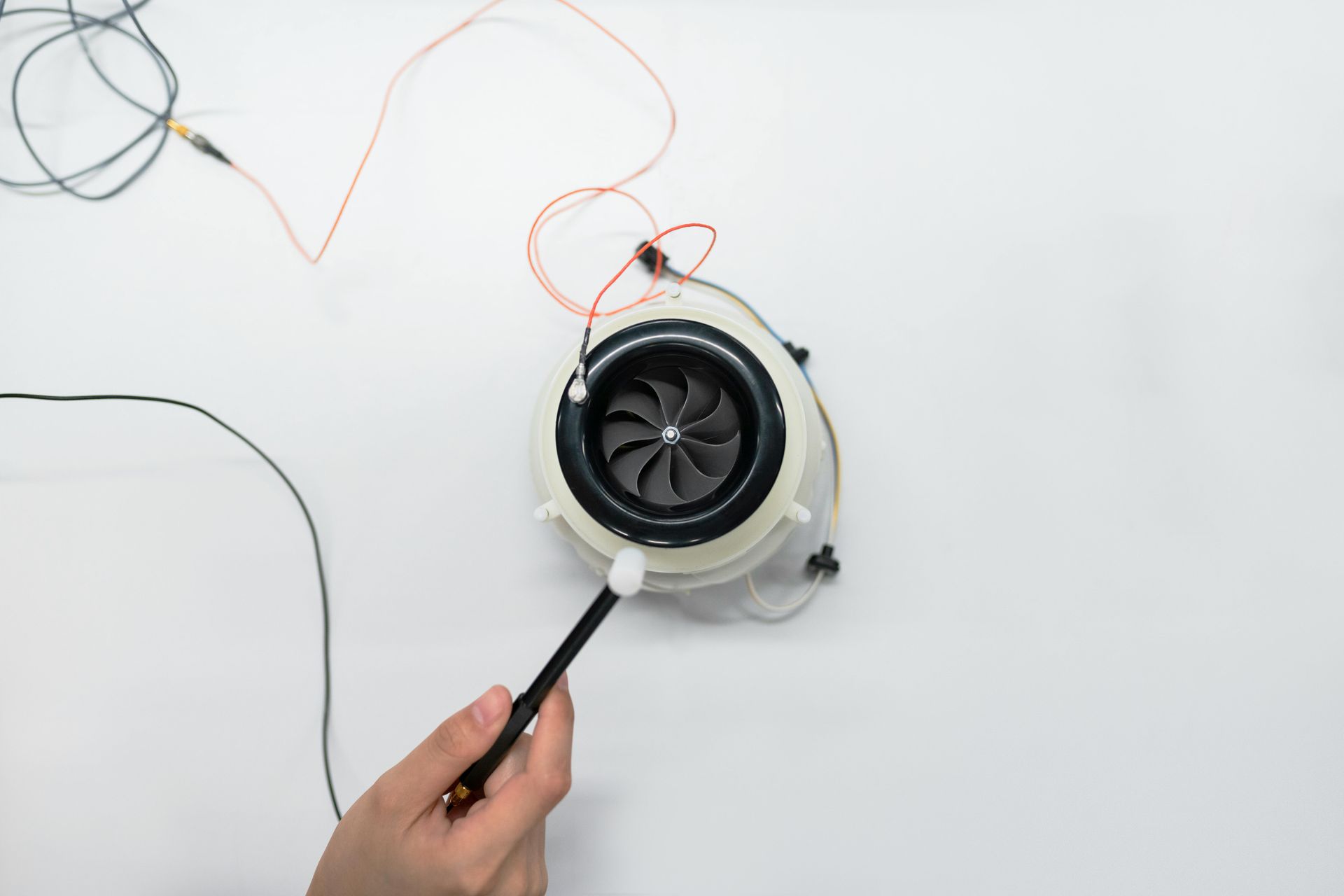 A person is holding a pen in front of a fan.