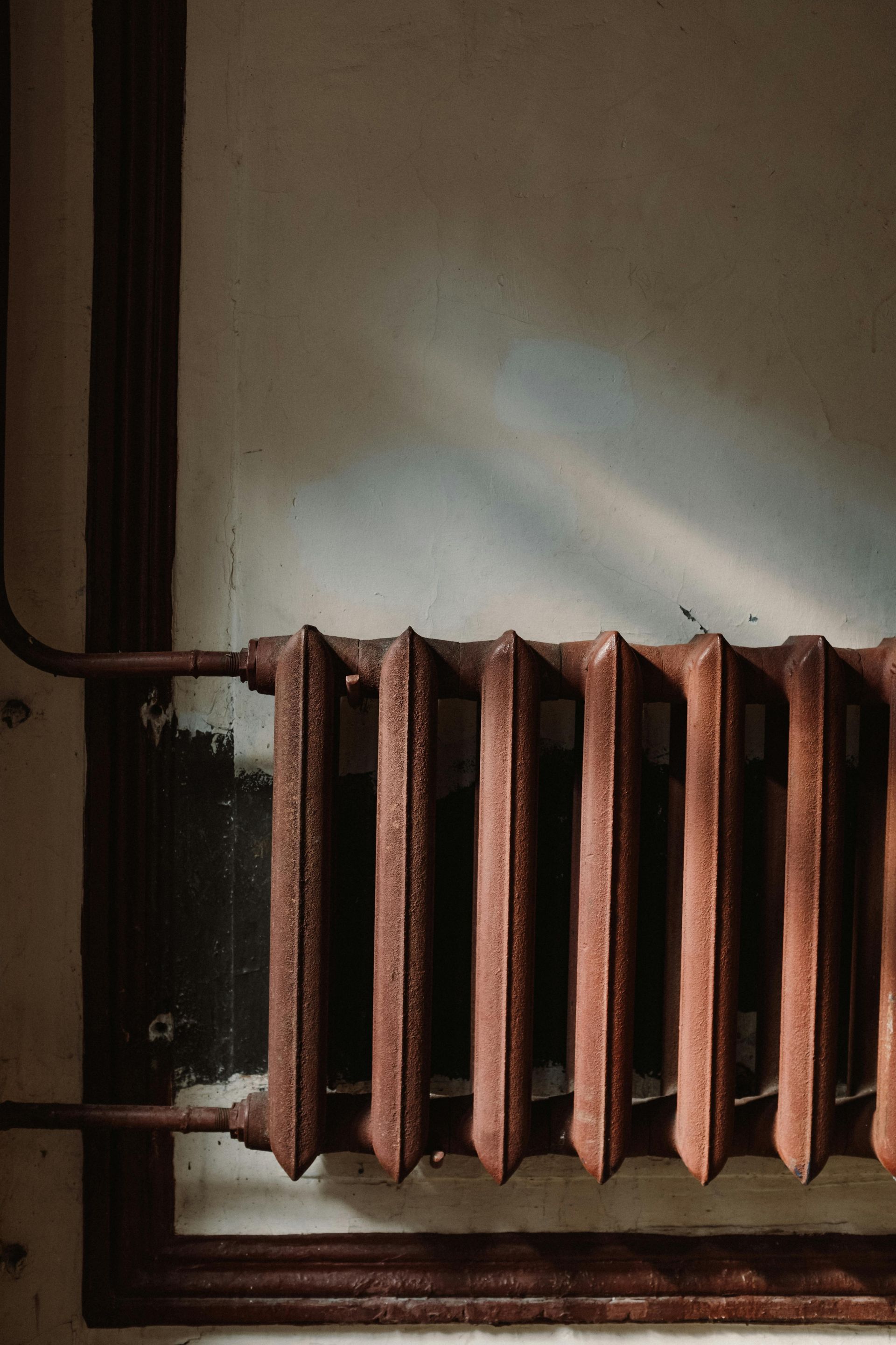 A close up of a rusty radiator on a wall.