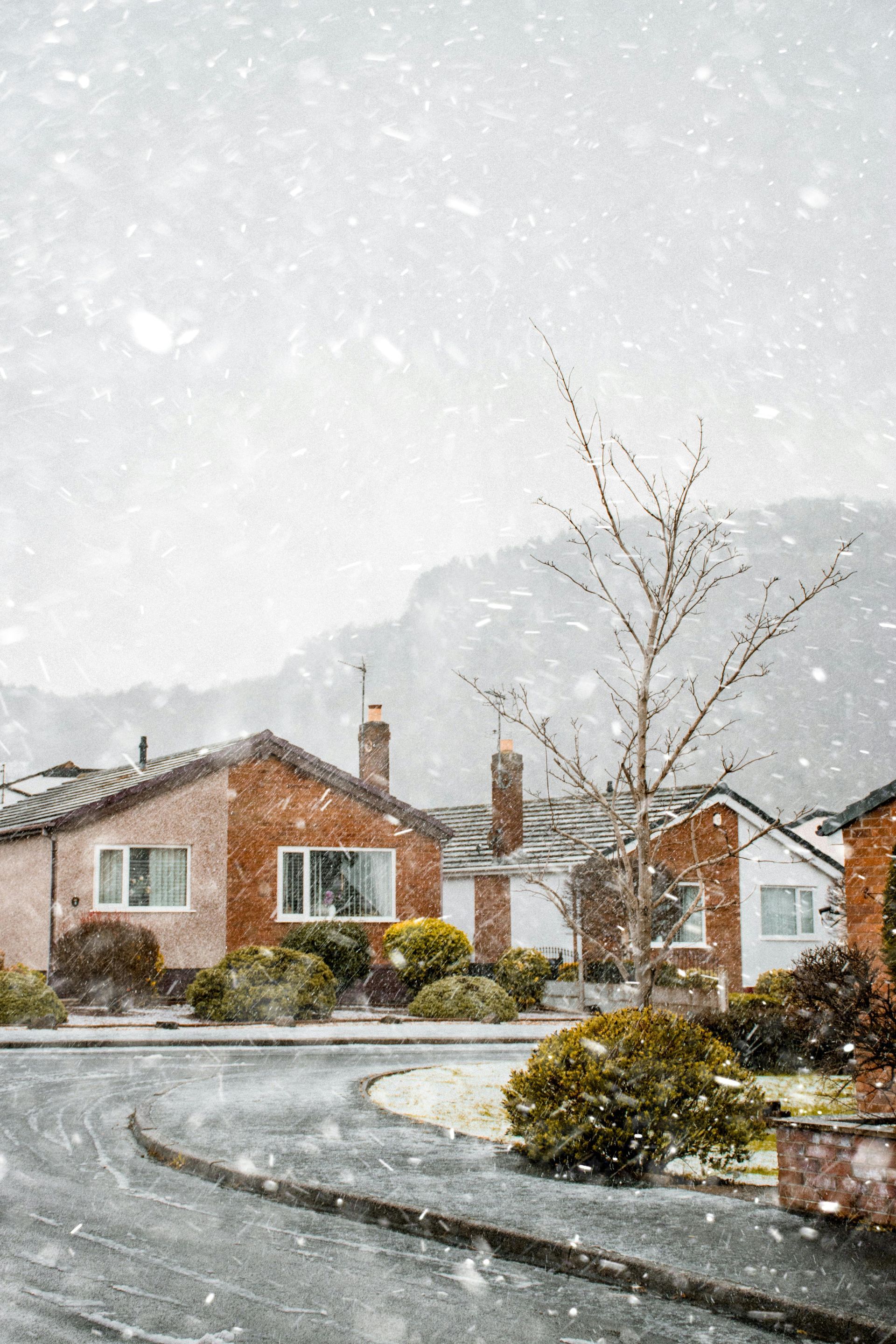 A row of houses in a snowy neighborhood with mountains in the background.