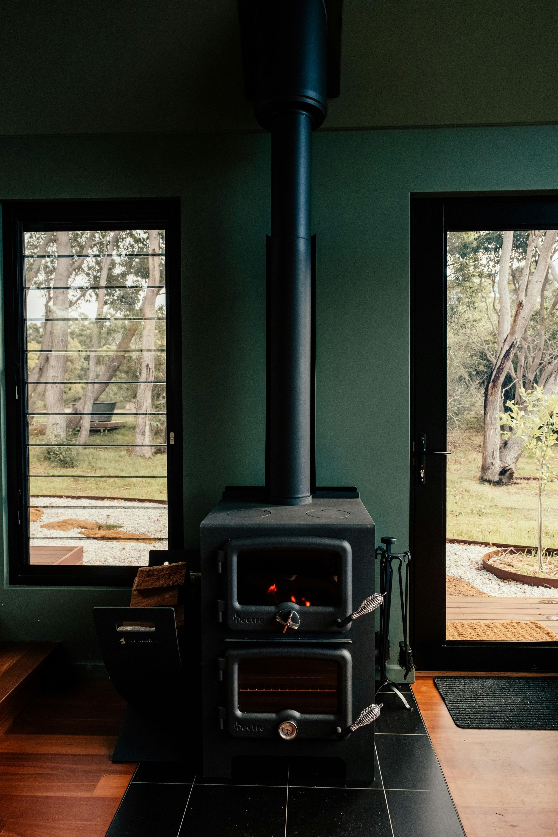 A wood stove is sitting in a room next to a window.