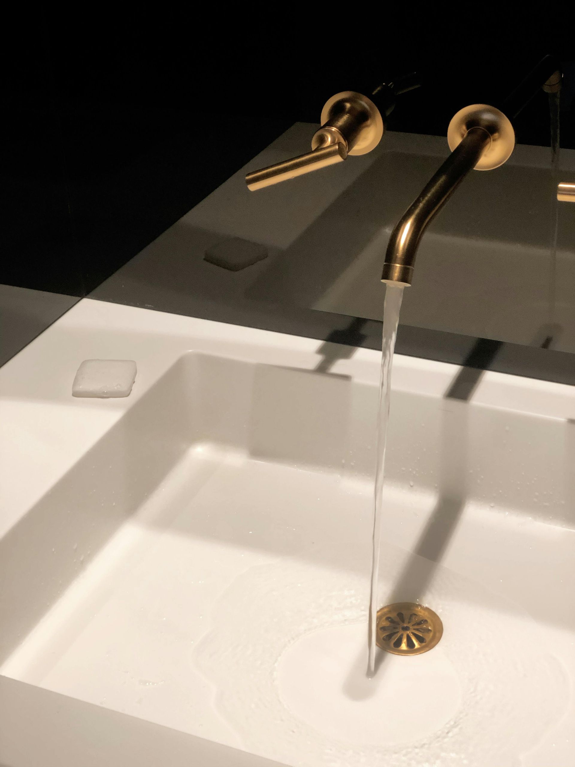 A bathroom sink with a gold faucet and soap dispenser