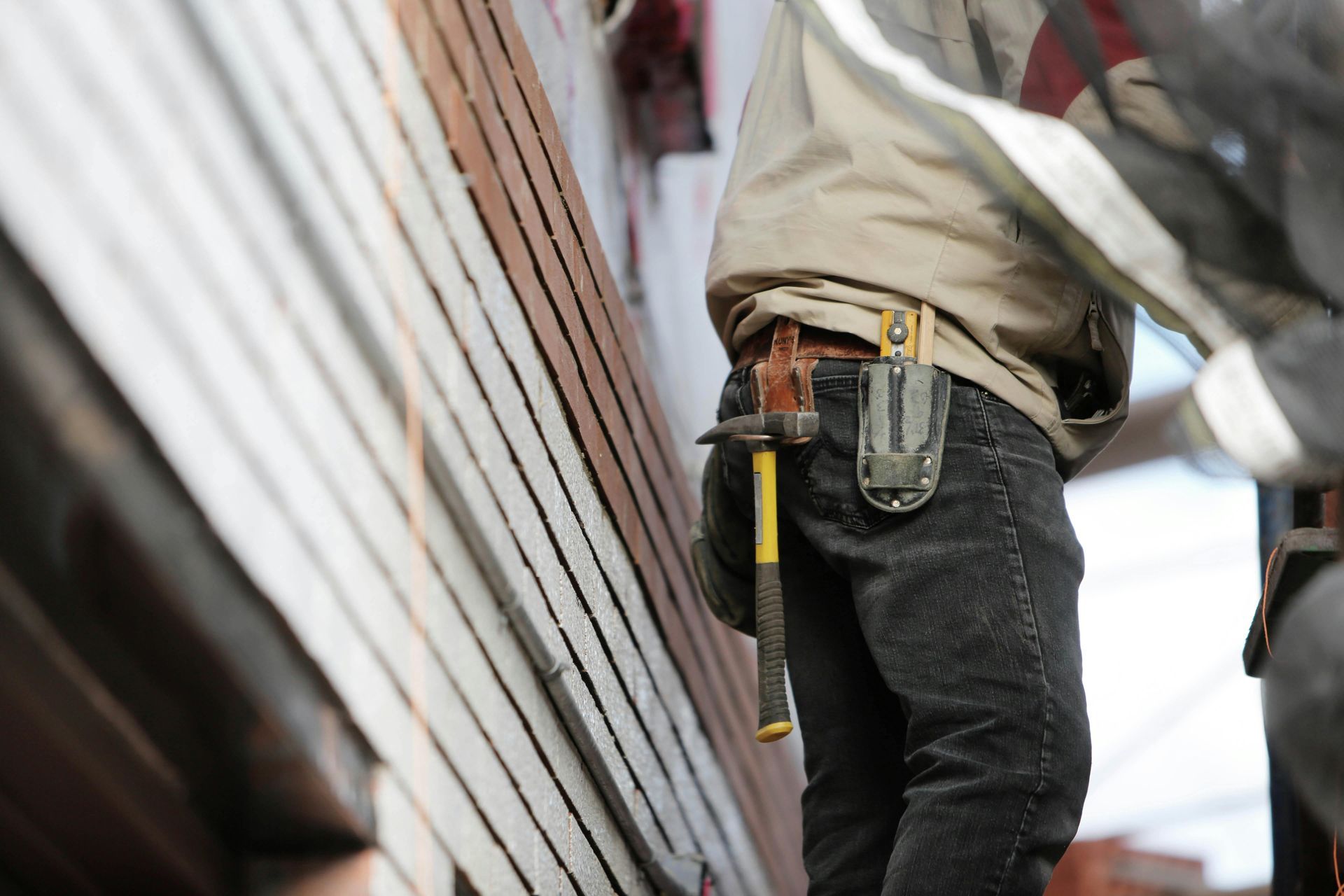 A man wearing a tool belt with a hammer in his pocket.