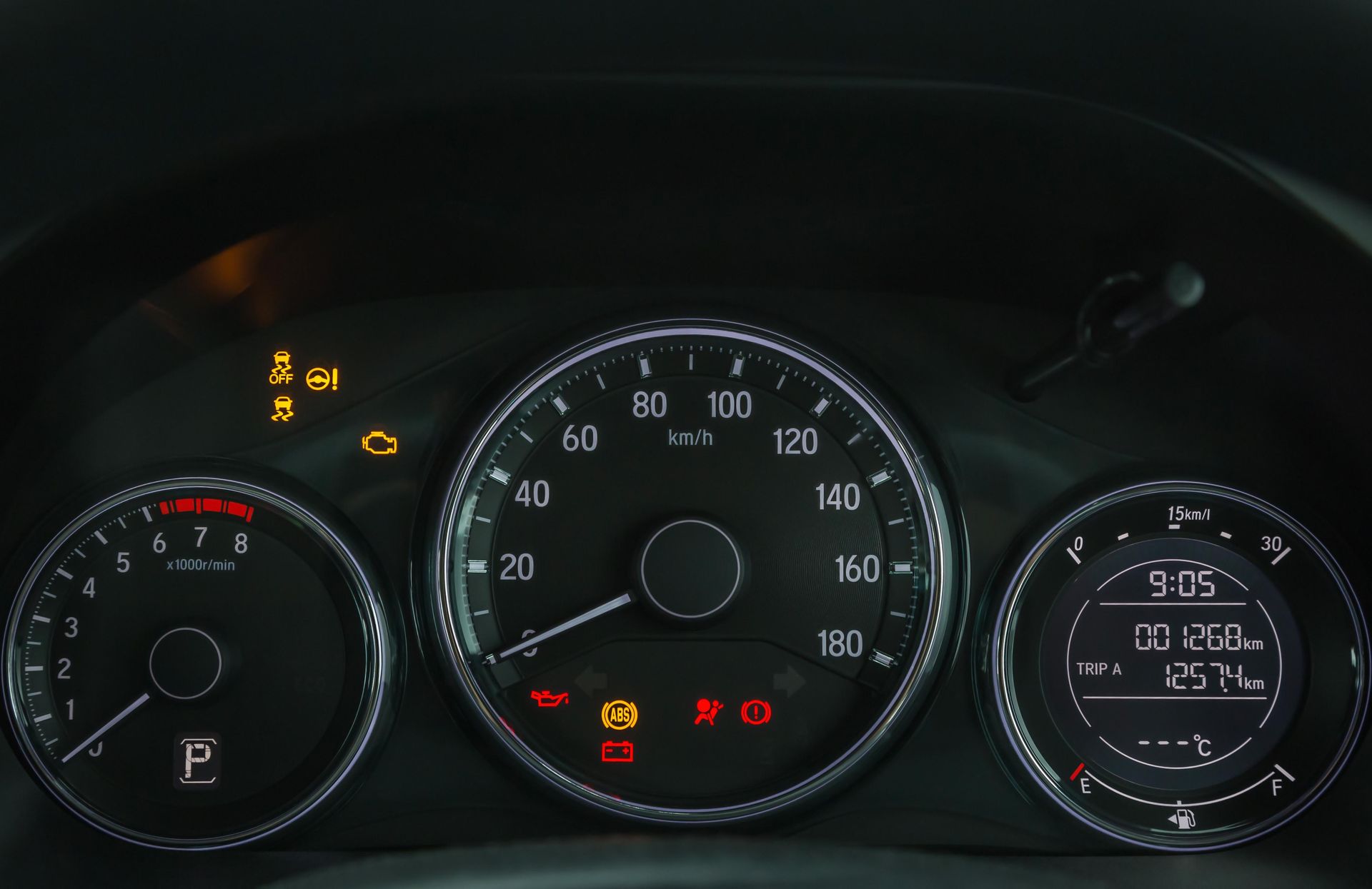 Car dashboard with illuminated warning lights, speedometer, and digital display showing car's status.