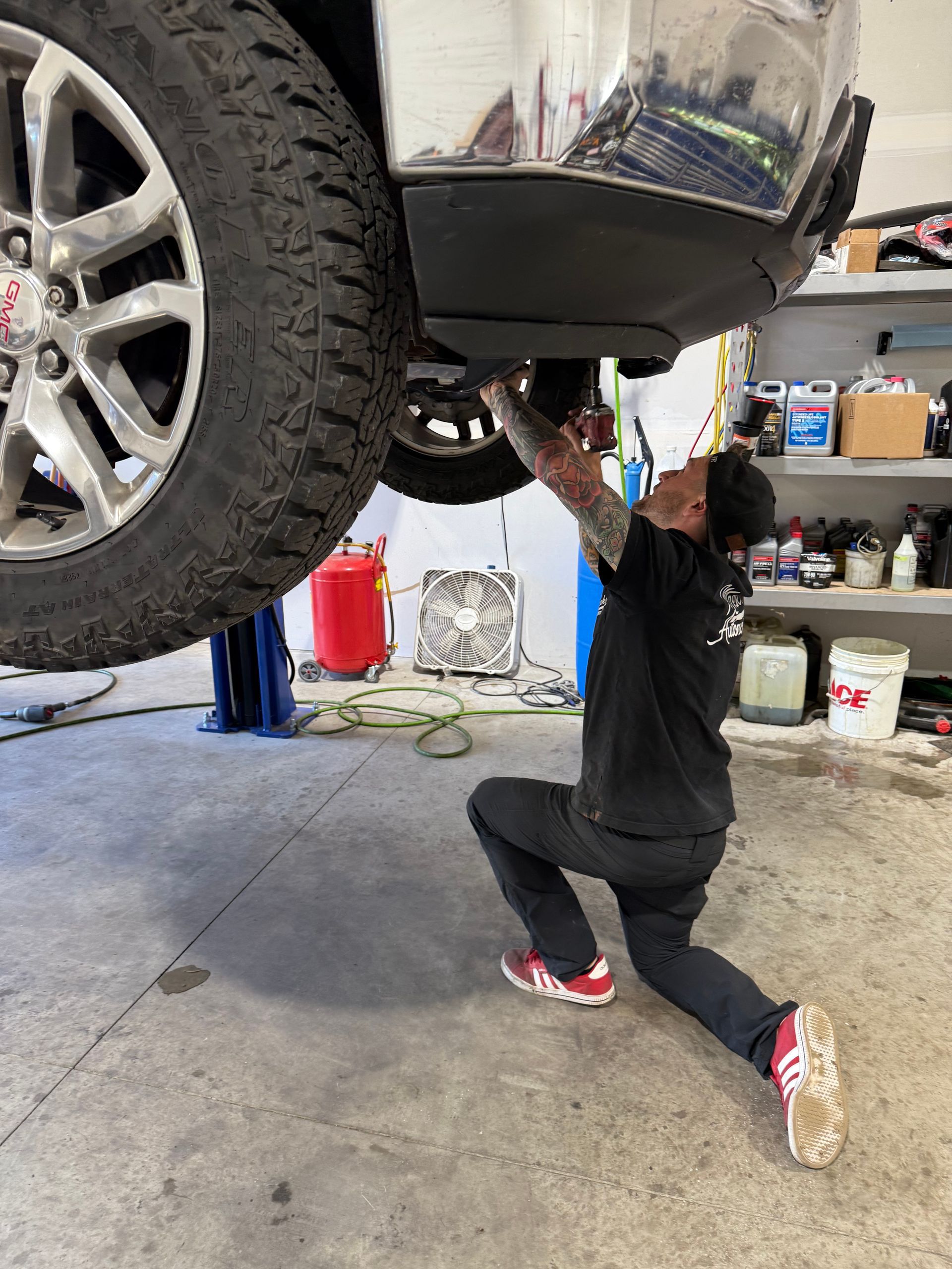 Car brake rotor and suspension components on a vehicle lifted in a repair shop.
