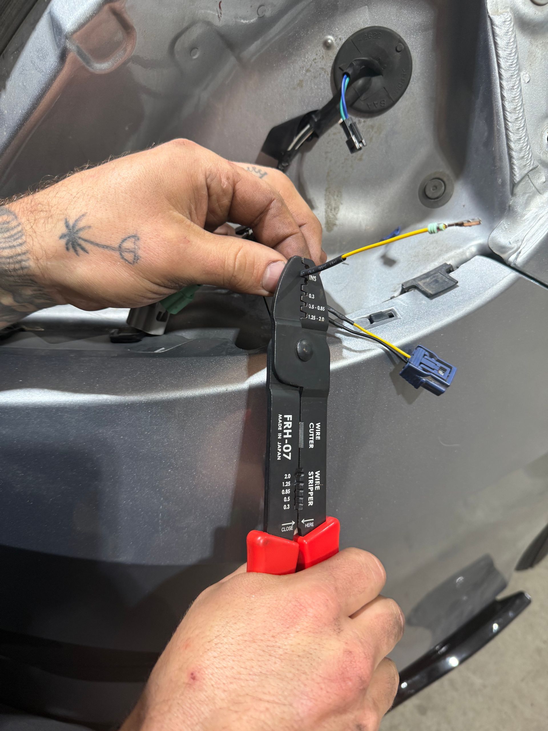 Mechanic connecting jumper cables to a car battery under the hood.
