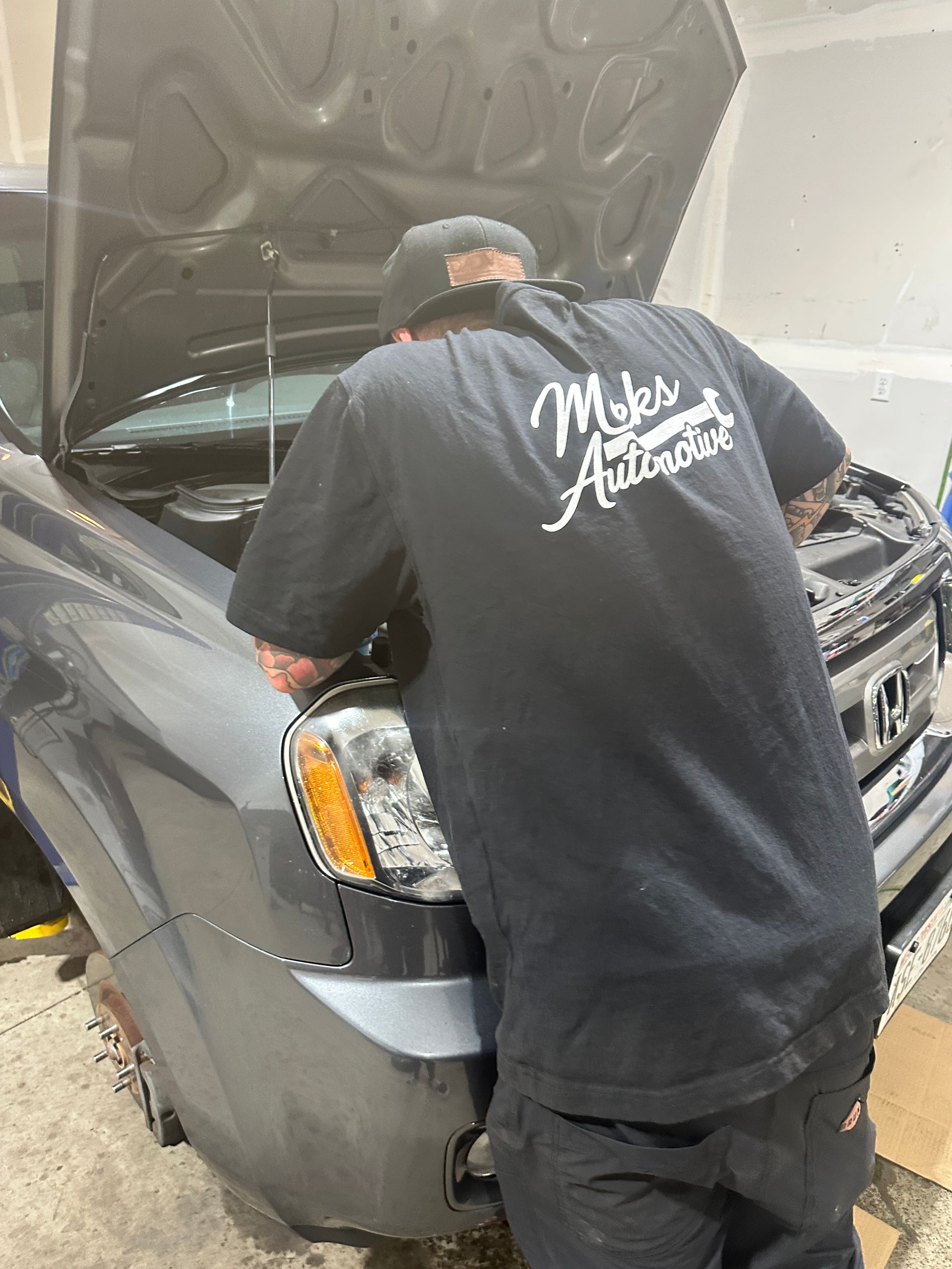 Mechanic's gloved hand checking oil level in a car engine bay. Blue sleeve, white glove, gray engine.