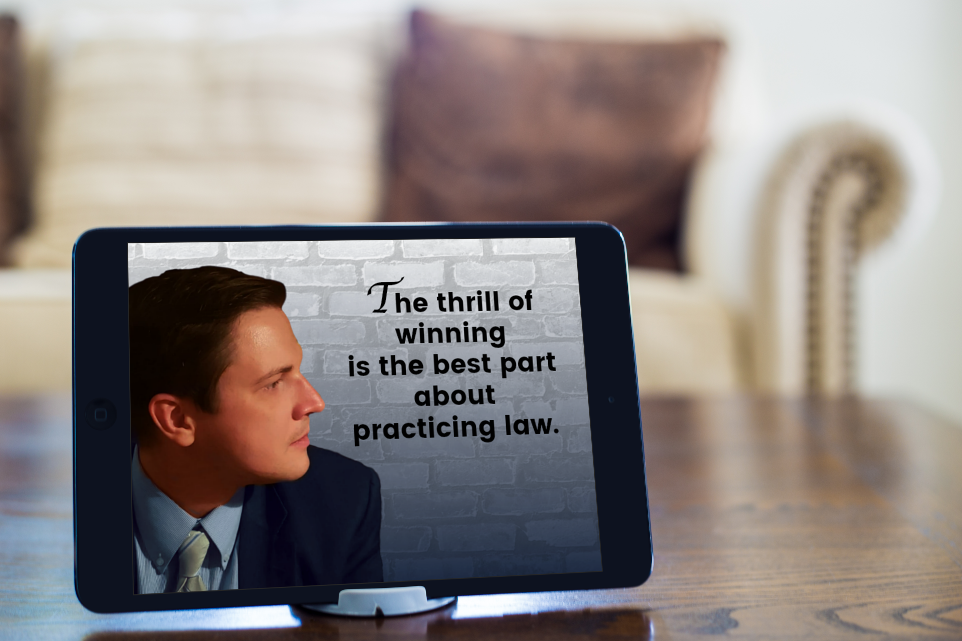 Quote by Experienced Litigator Daniel Zdrodowski that says the thrill of winning is the best part of practicing law showing on an ipad near a sofa