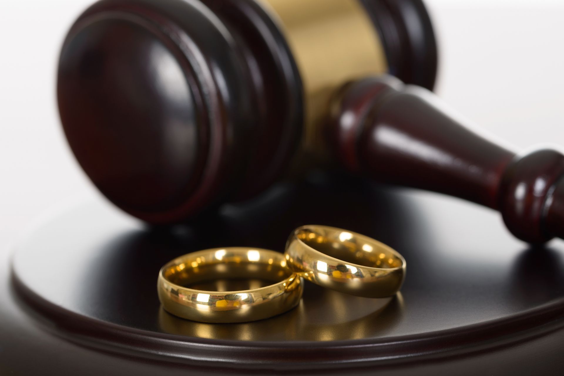 A pair of wedding rings sitting next to a judge 's gavel