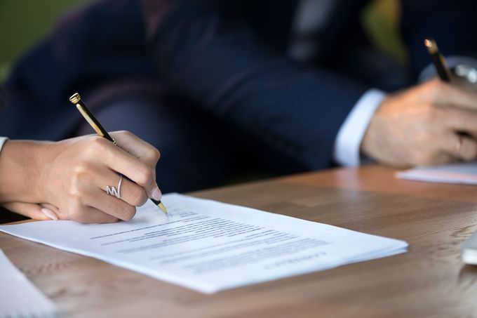 A man and a woman are signing a document on a table.