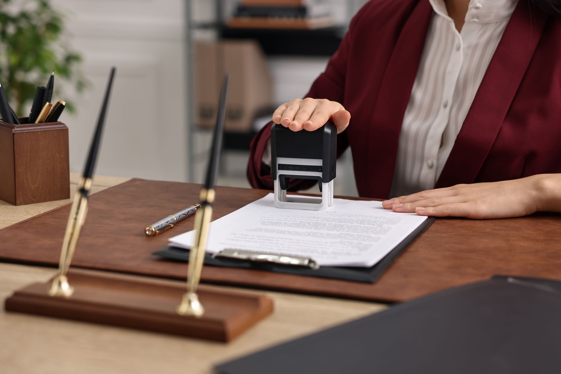 A woman is sitting at a desk using a stamp on a piece of paper.