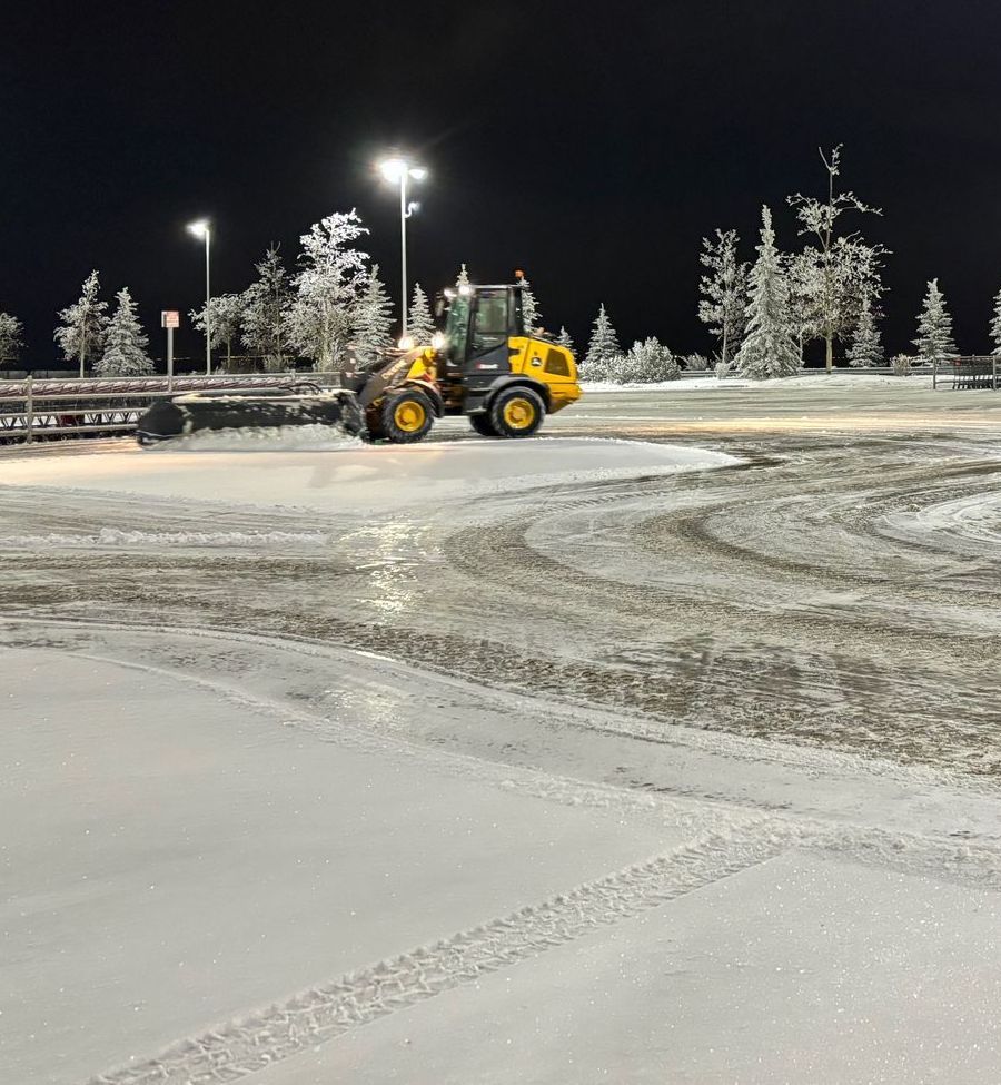 a yellow tractor is clearing snow from the ground