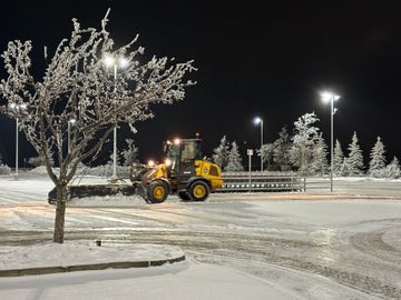 a man is using a snow blower on a snowy road