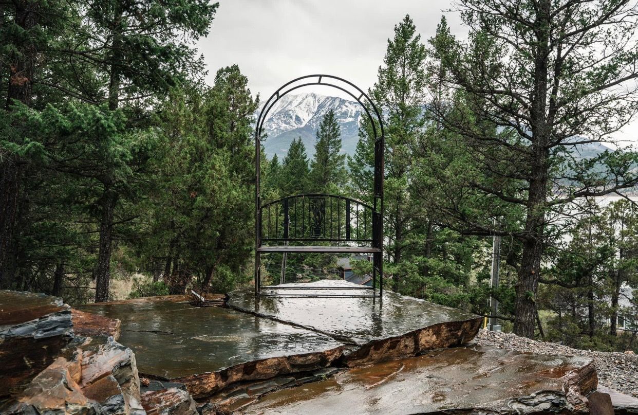 a garden filled with rocks and trees with a white tent in the background