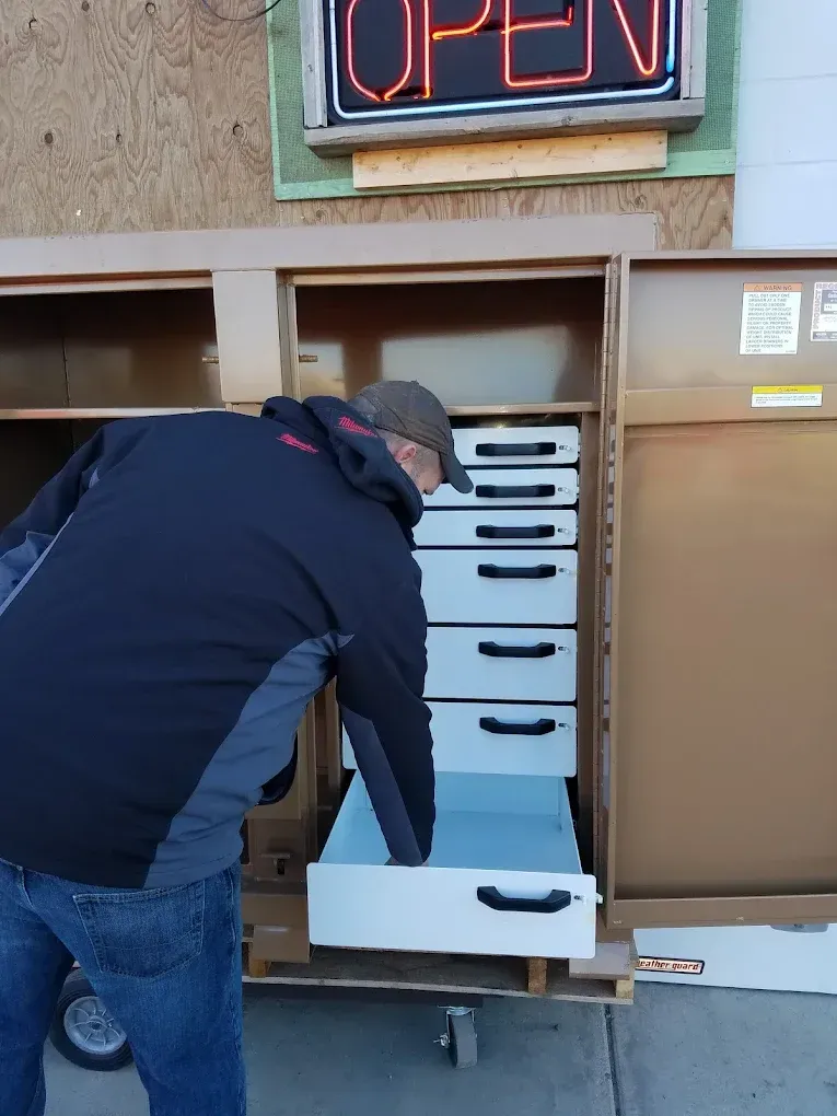 A man is opening a drawer under an open sign