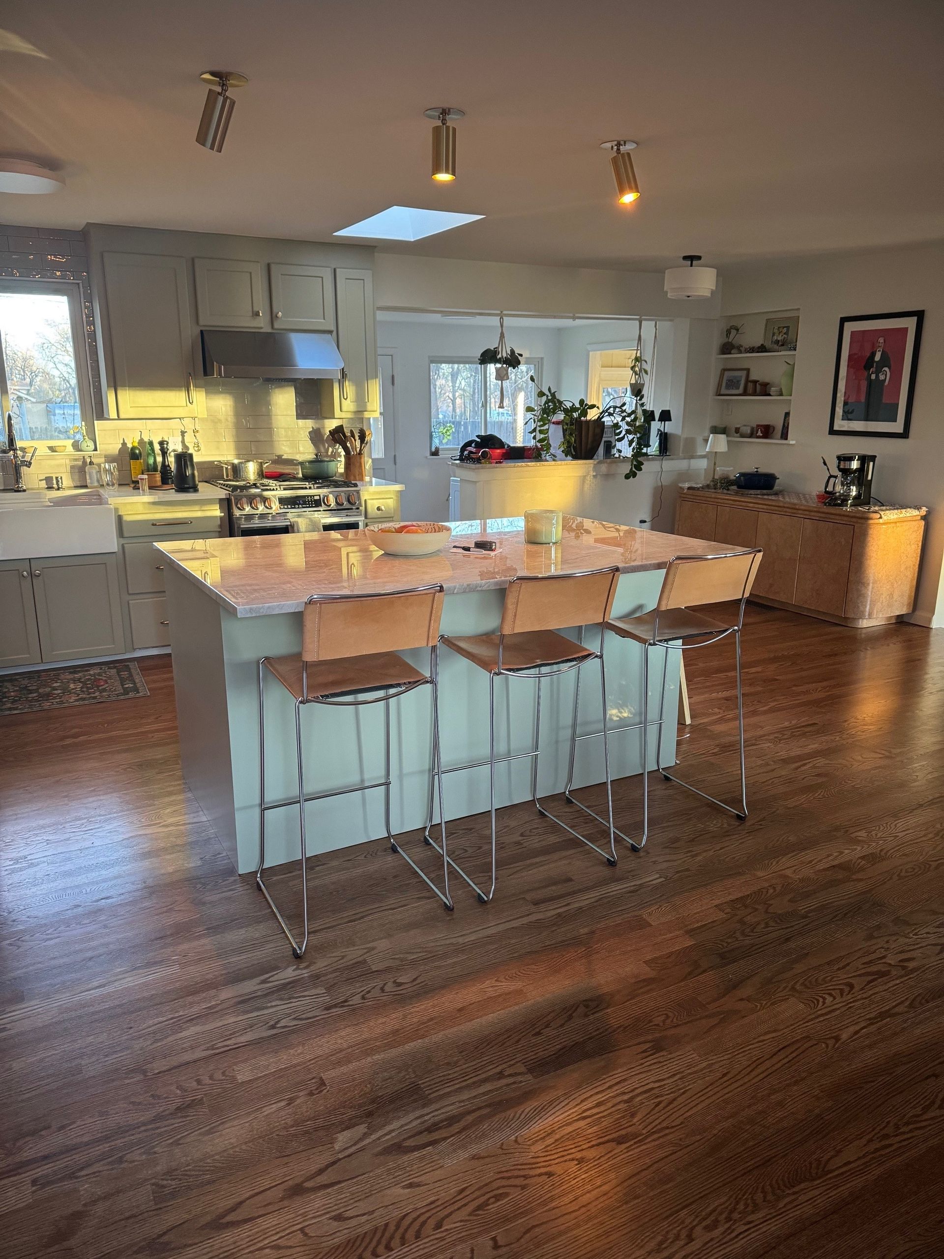 Kitchen with blue island, wood countertops, and bar stools; hardwood floor; gray cabinets.