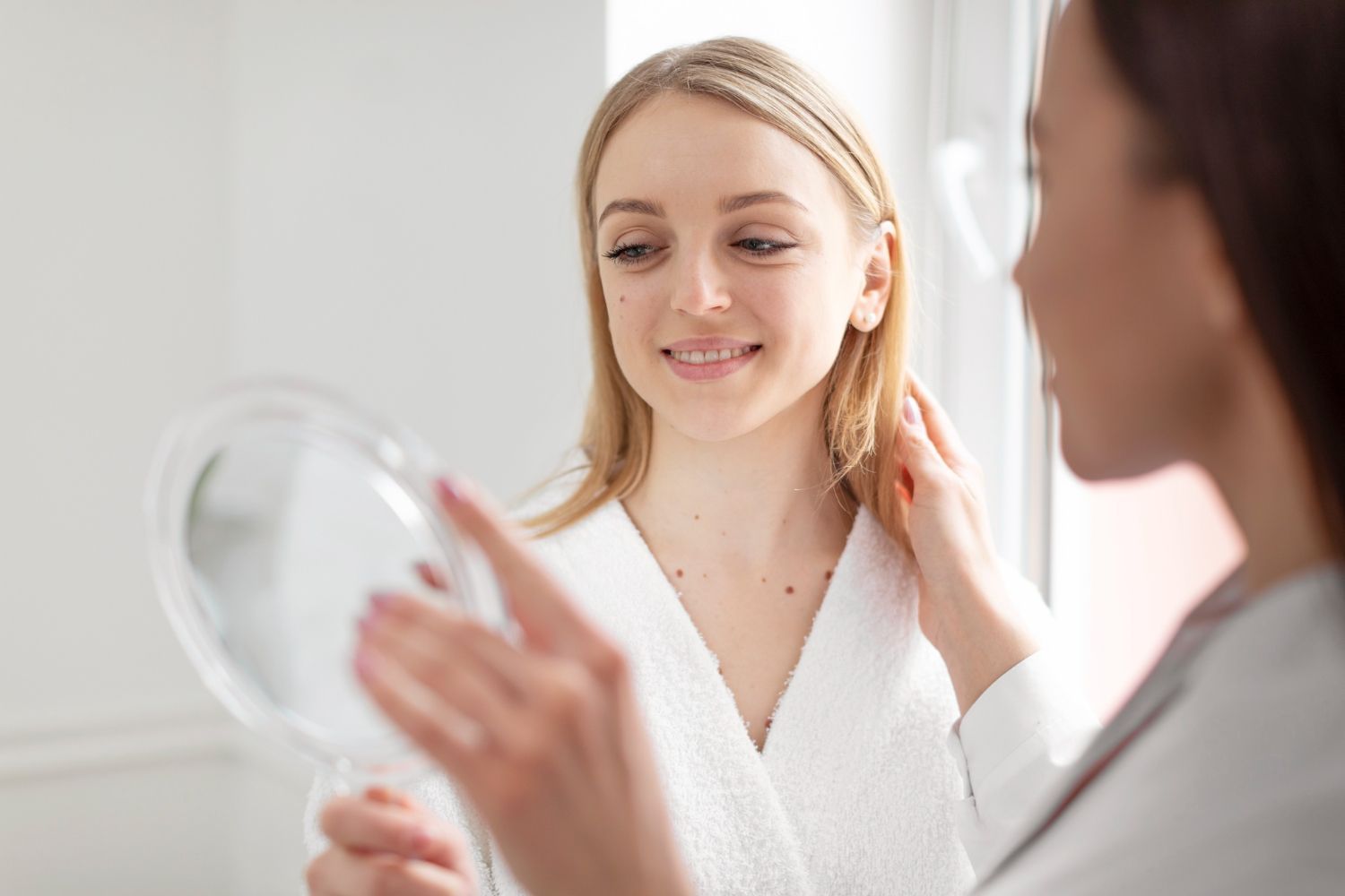 A woman is looking at herself in a mirror.