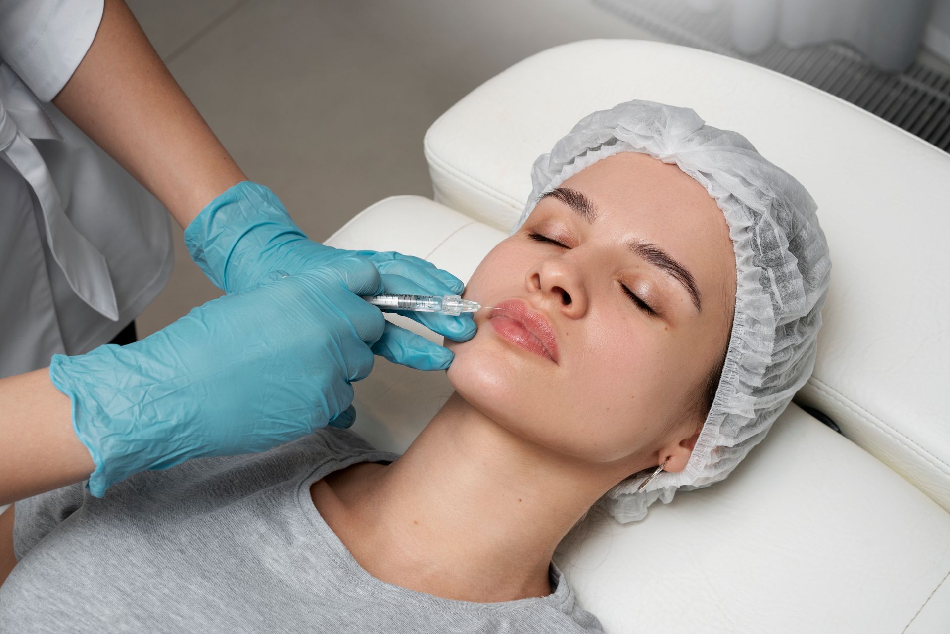 A woman is getting a botox injection in her lips.