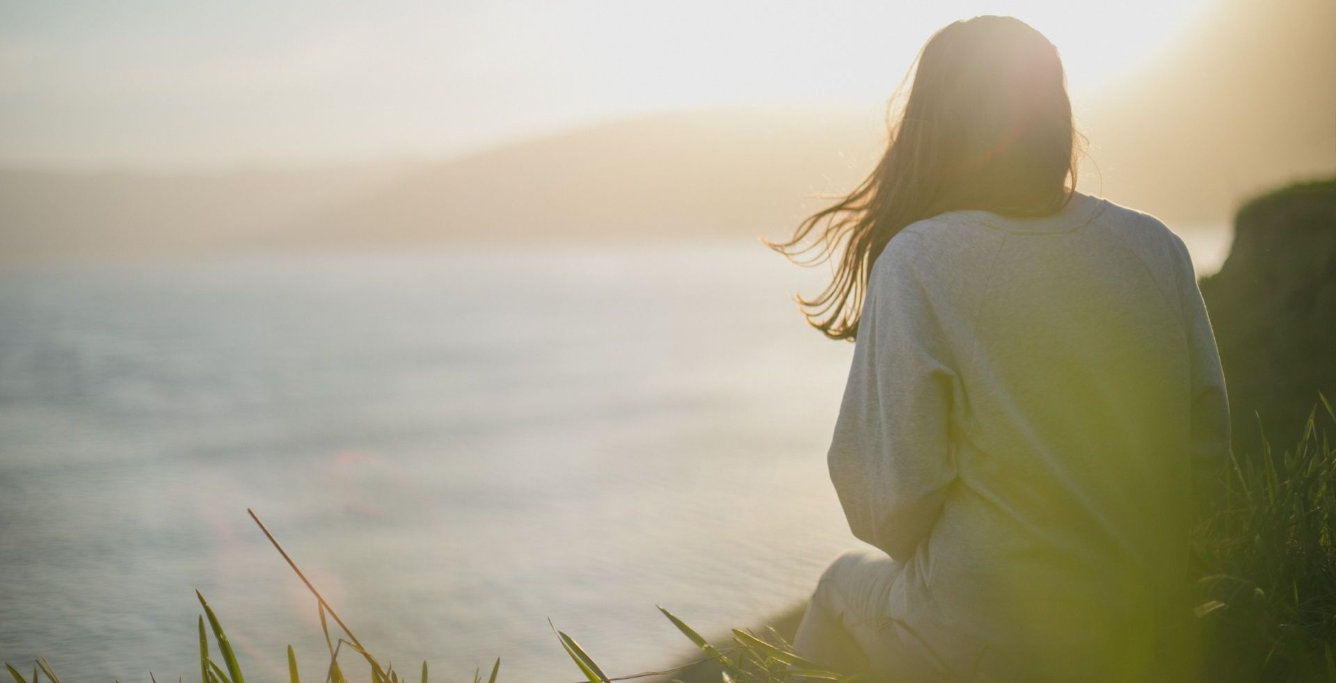 a woman is sitting on a cliff overlooking the ocean.