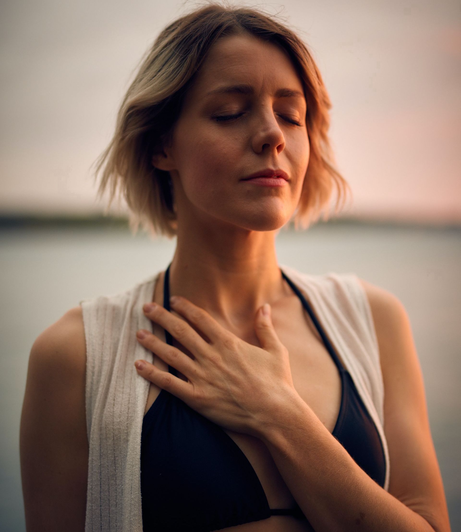 a woman in a bikini is holding her hand to her chest.