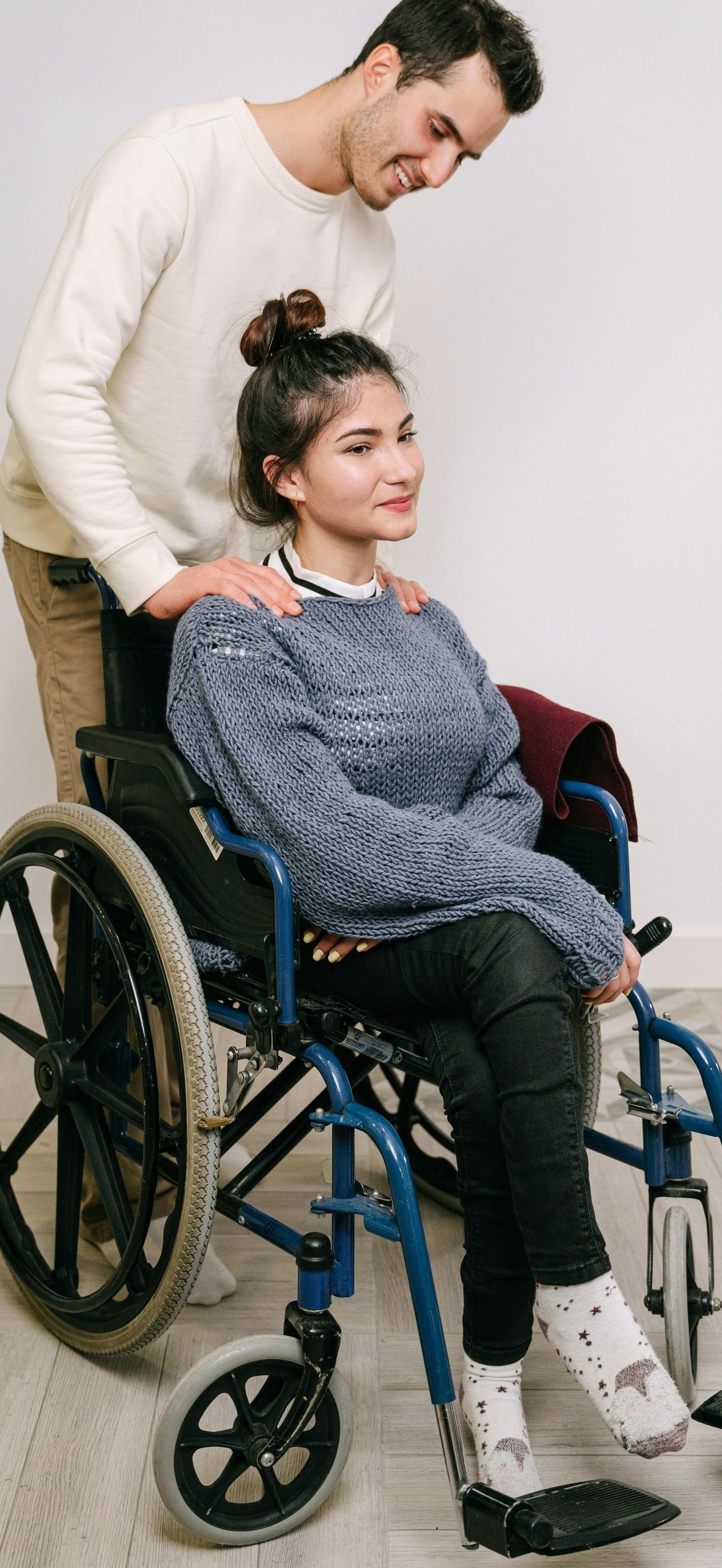 A man is helping a woman in a wheelchair.