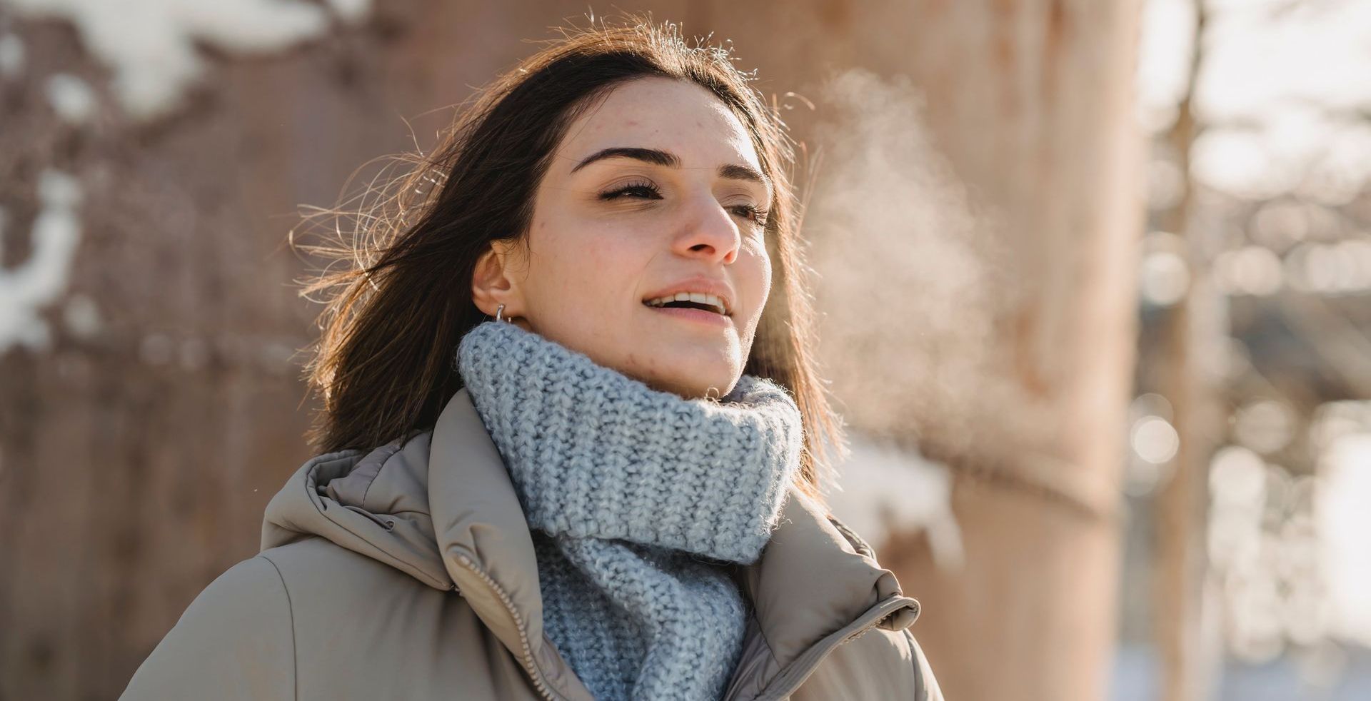 a woman wearing a sweater and scarf is standing in the snow.