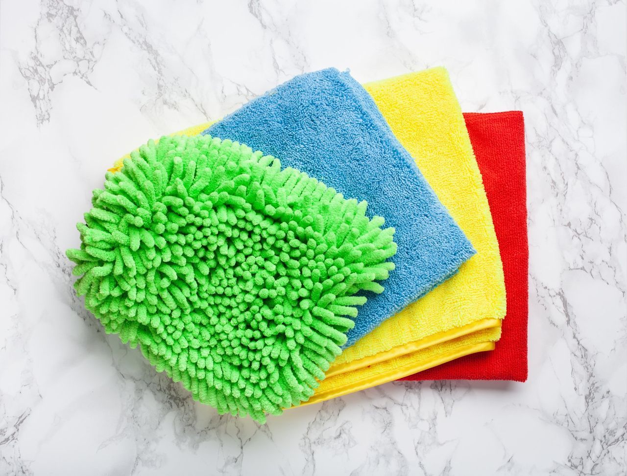 A stack of colorful microfiber towels on a marble surface.