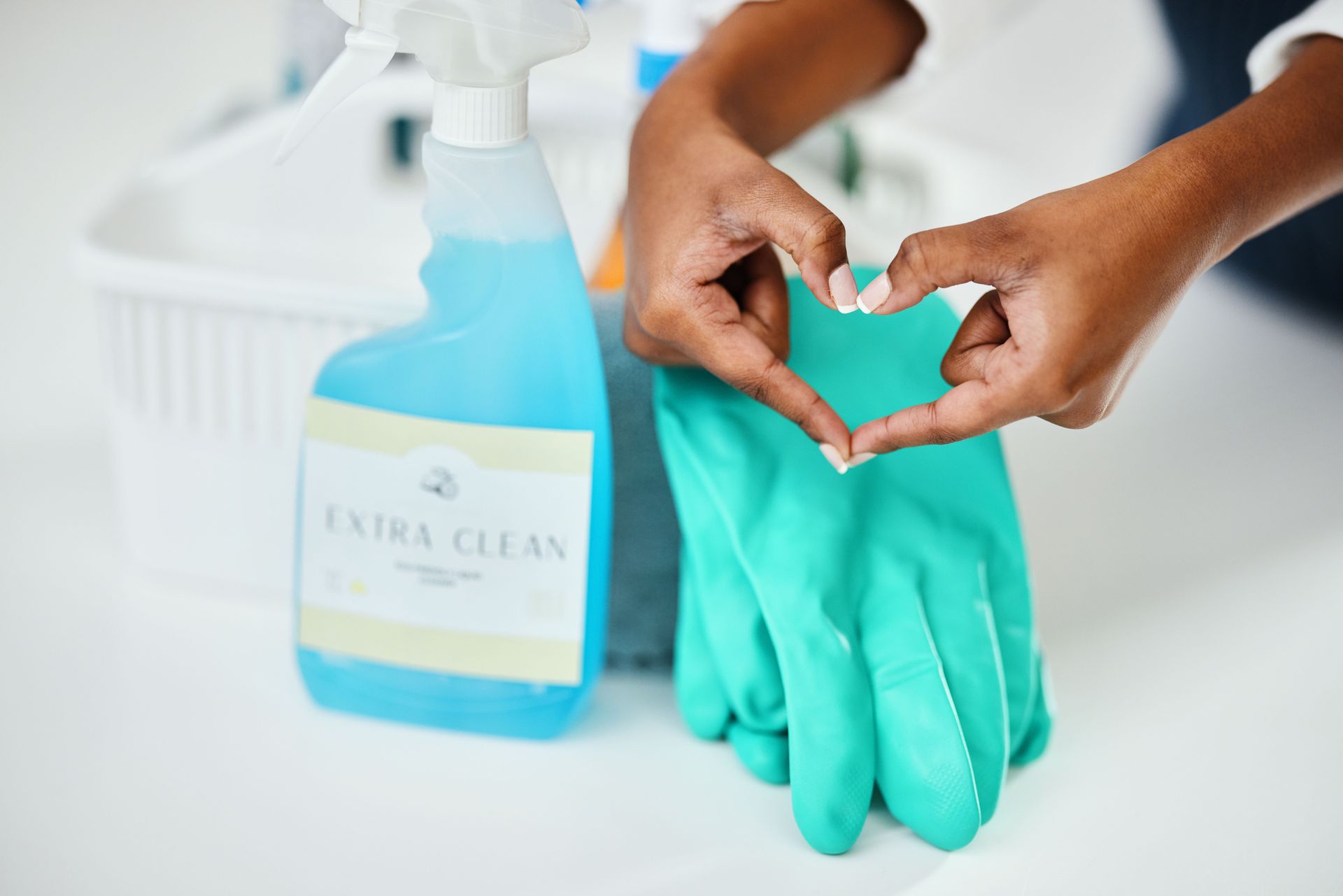A person is making a heart shape with their hands on a pair of cleaning gloves.