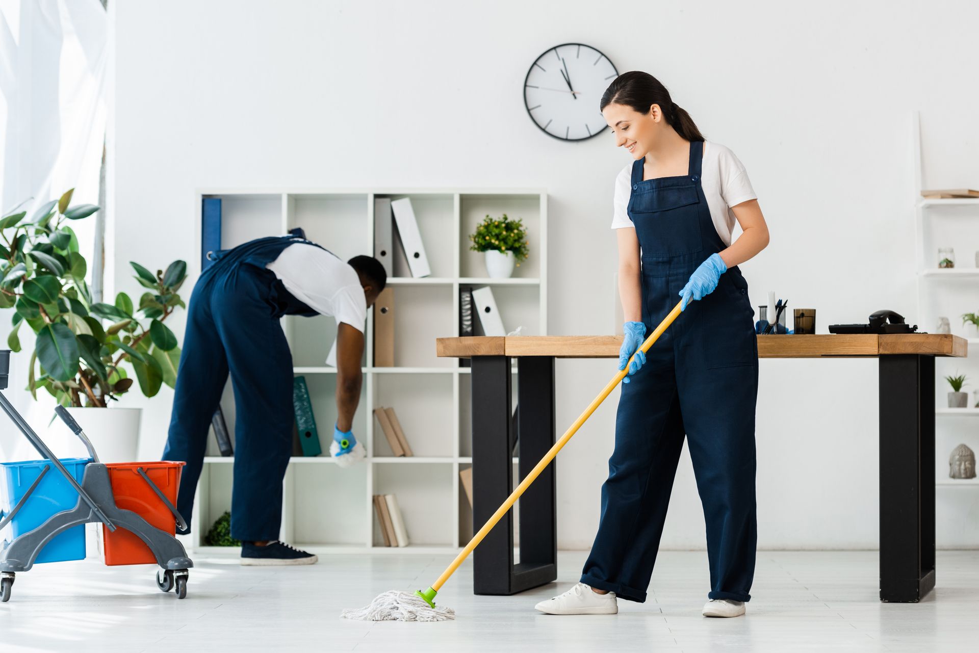 A man and a woman are cleaning the floor in an office.