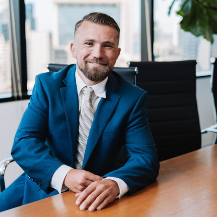 A real estate agent hands keys to a couple sitting at a desk during a professional meeting in an office.