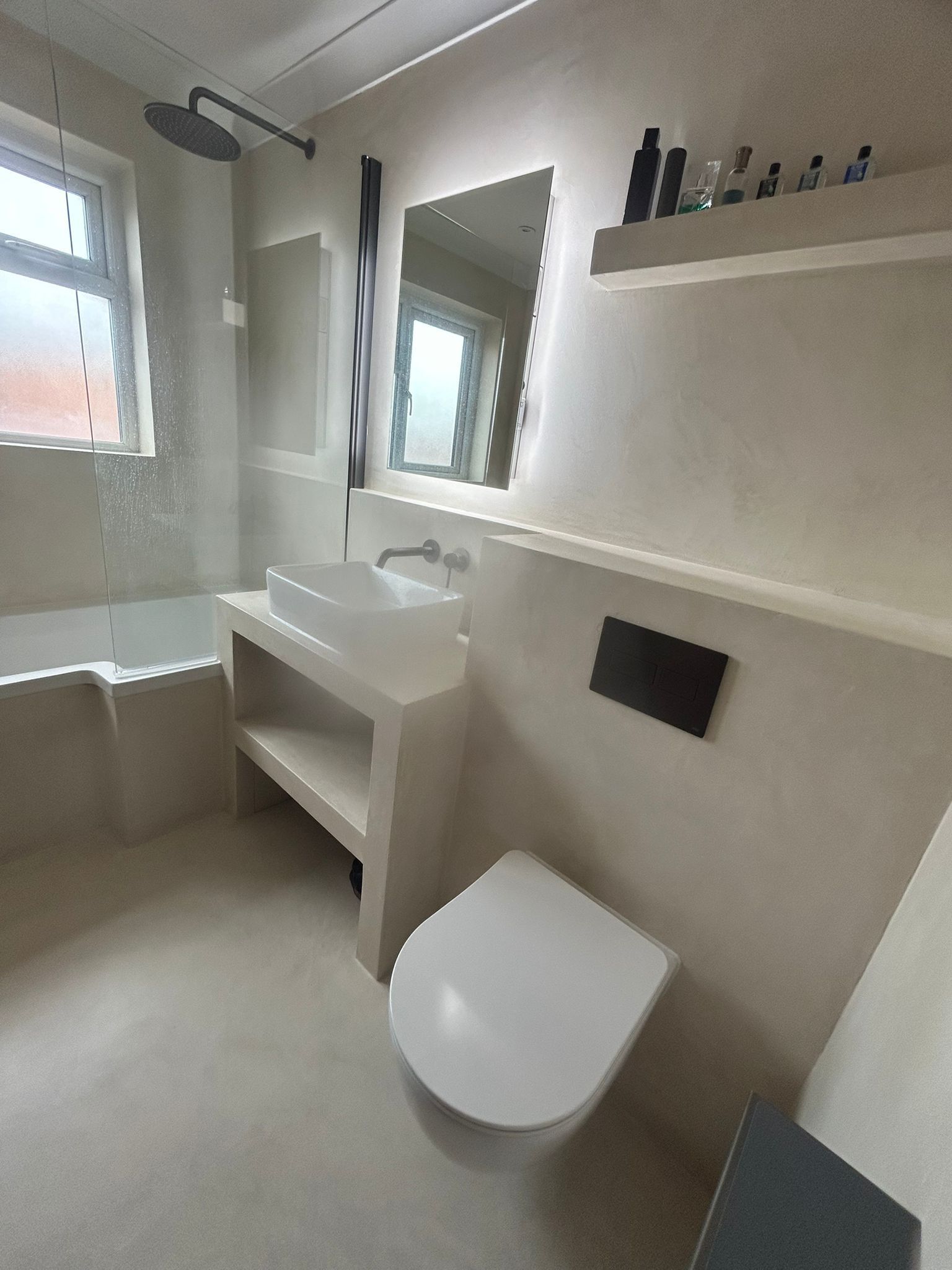 Modern bathroom with a bathtub, toilet, sink, and mirror; all in neutral tones.