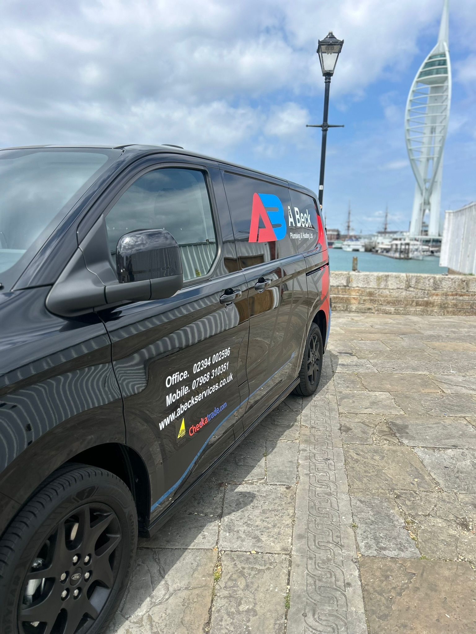 Black van with business logo parked near a waterfront. Spinnaker Tower visible in the background.