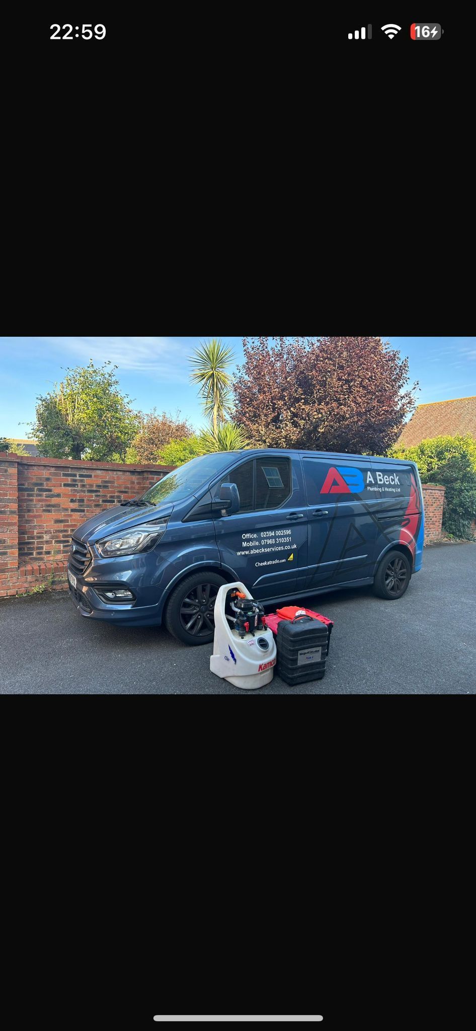 Blue van parked on a driveway with cleaning equipment in front of it.