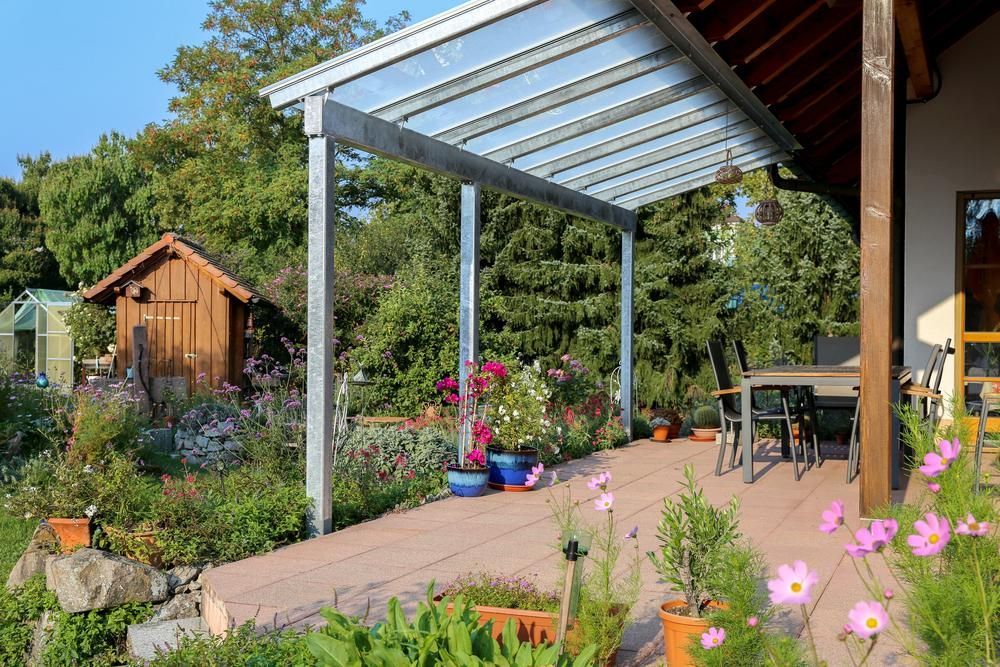 A Patio With Flowers and a Table and Chairs Under a Canopy — Lakecrest Projects in Belmont North, NSW