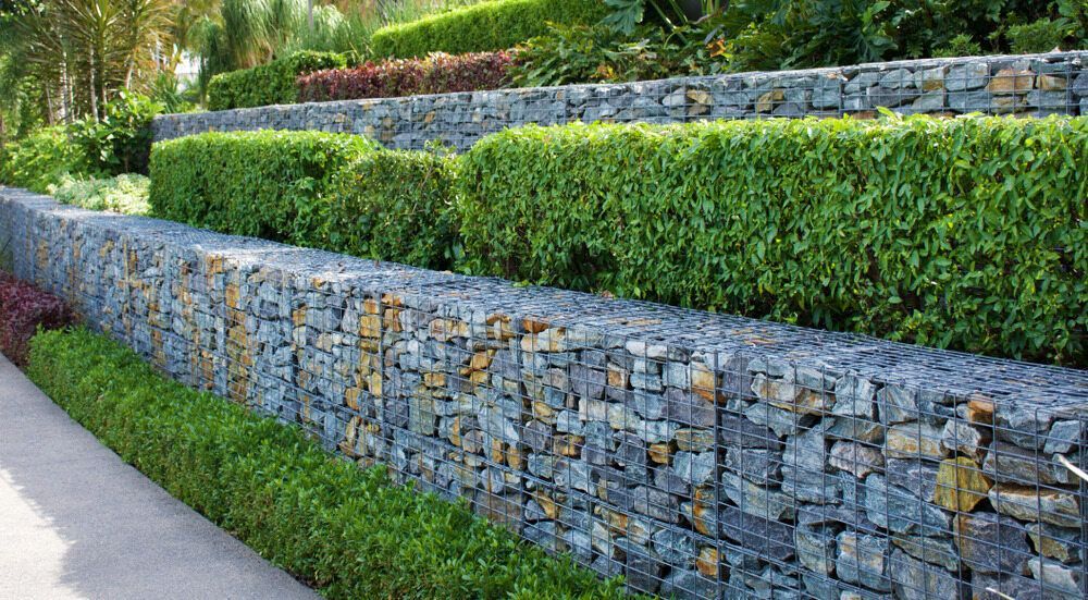 A Stone Wall Surrounded by Bushes and Trees in a Garden — Lakecrest Projects in Lake Macquarie, NSW