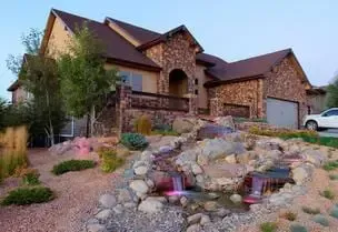 House with stone exterior, water feature, and landscaping.