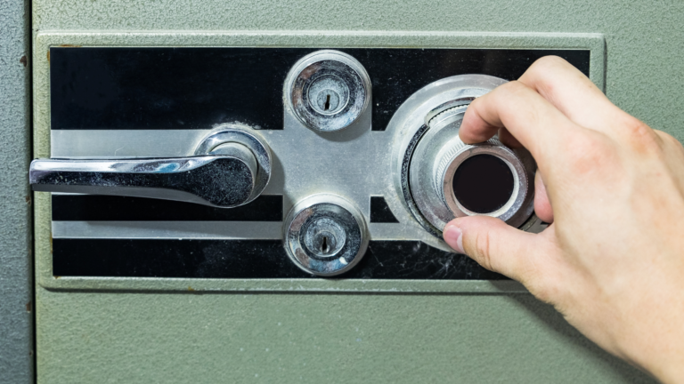 A man wearing black gloves is working on a safe.