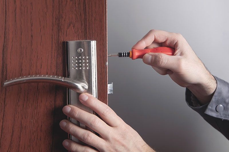 A worker installing a door knob, close-up of woodworker's hands.