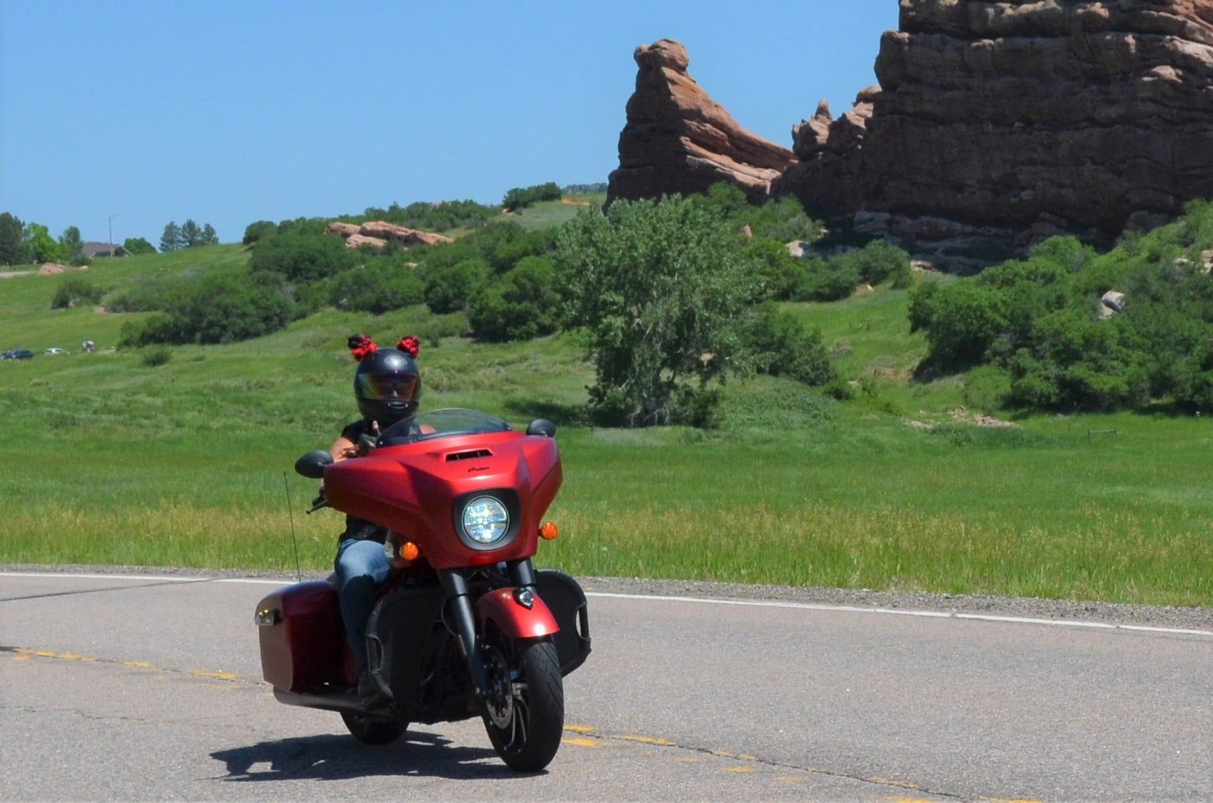A person is riding a red motorcycle down a road